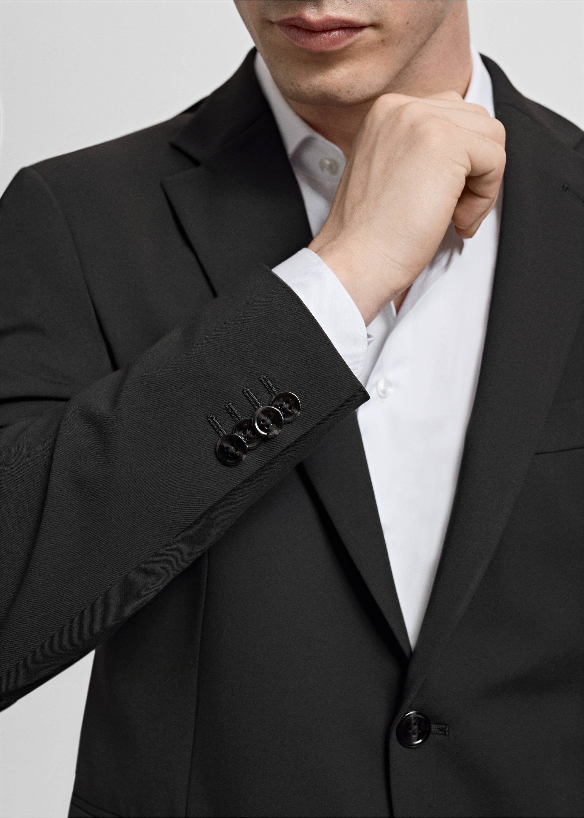 Close-up of a black blazer with lapels and buttoned cuffs worn over a white shirt., Black. Ref: 17009607-00.