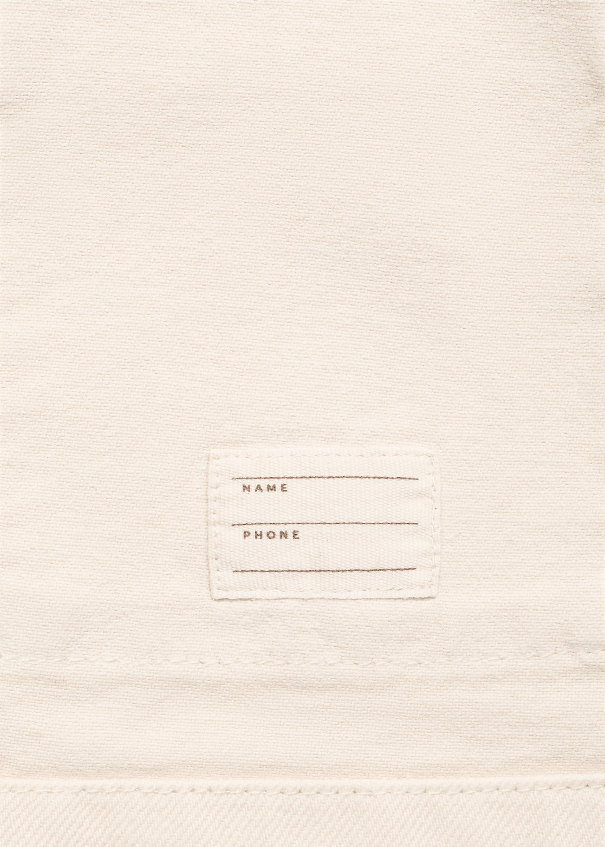 Close-up of a beige kids jacket fabric showing a personal name and phone label., Sand. Ref: 17073303-00.