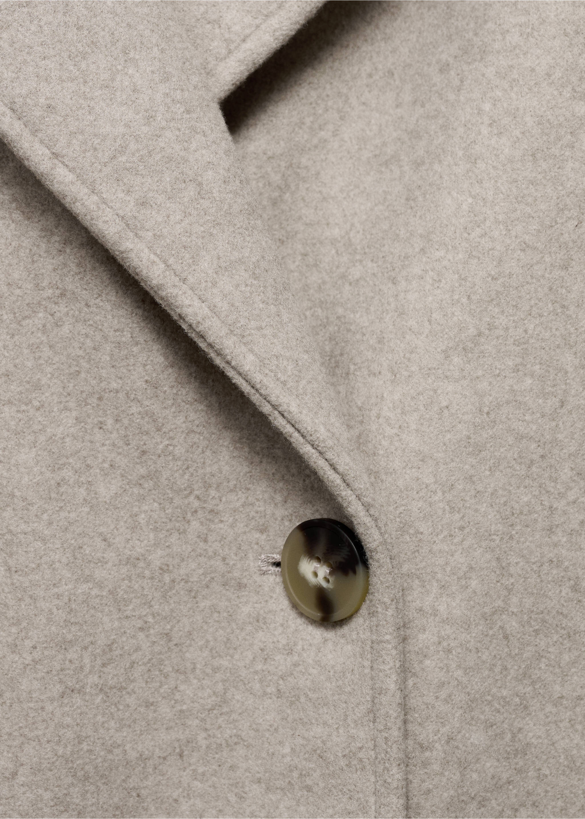 Close-up of a light beige coat fabric, lapel and tortoiseshell button., Medium Brown. Ref: 17095812-00.