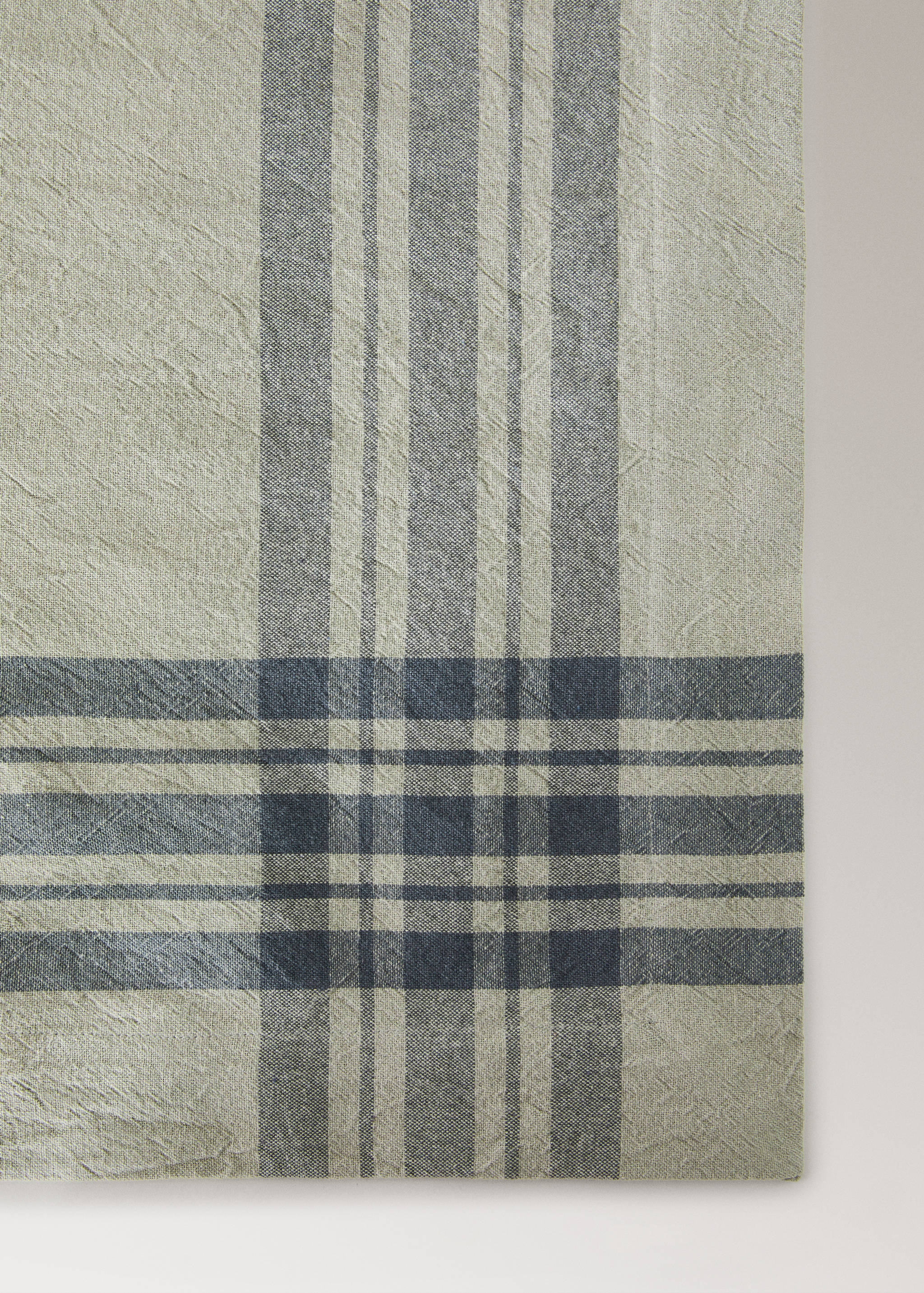 Close-up of a beige tablecloth with a grey and dark blue plaid pattern.