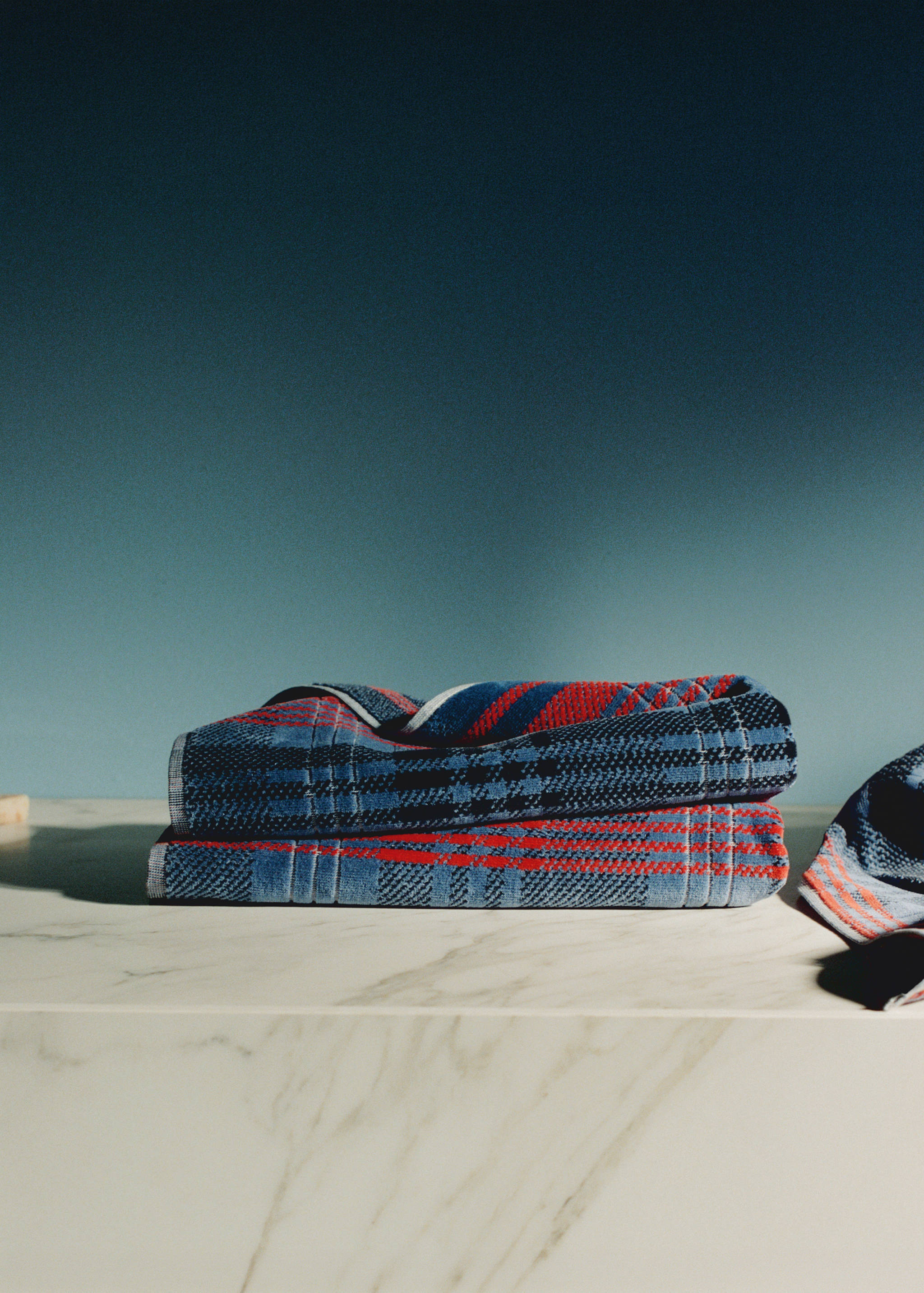 Folded blue and red plaid towel on a marble surface.