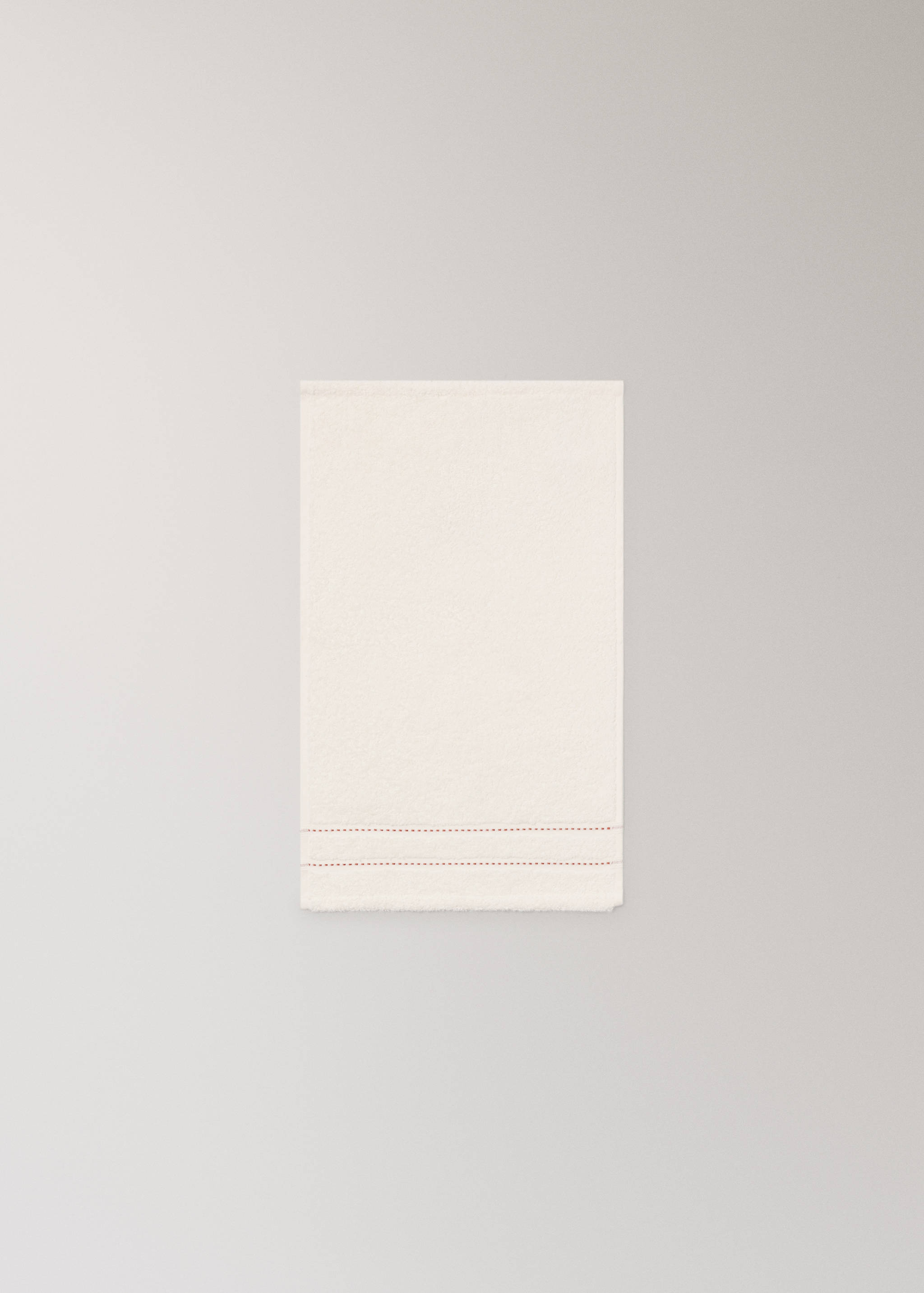 Off-white cotton towel with red stitching detail.