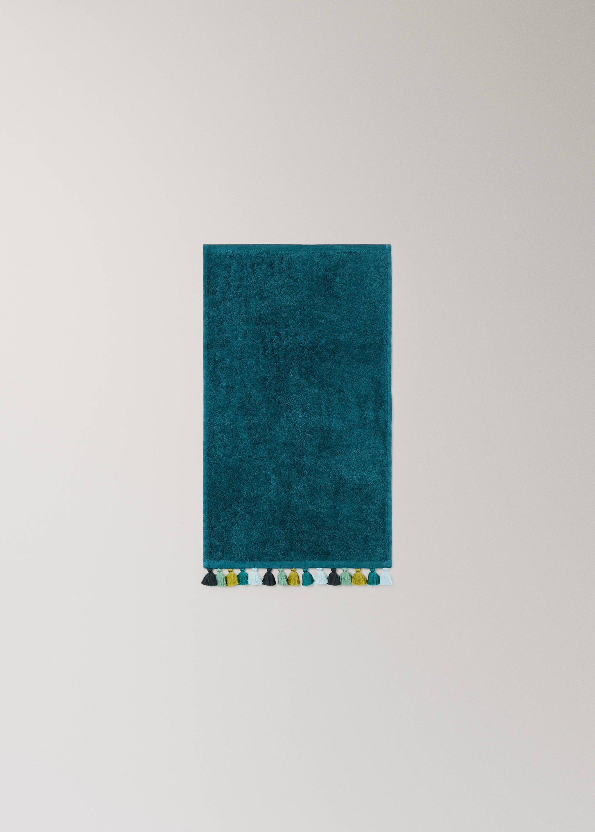 Teal towel with textured finish and multi-coloured tassels.