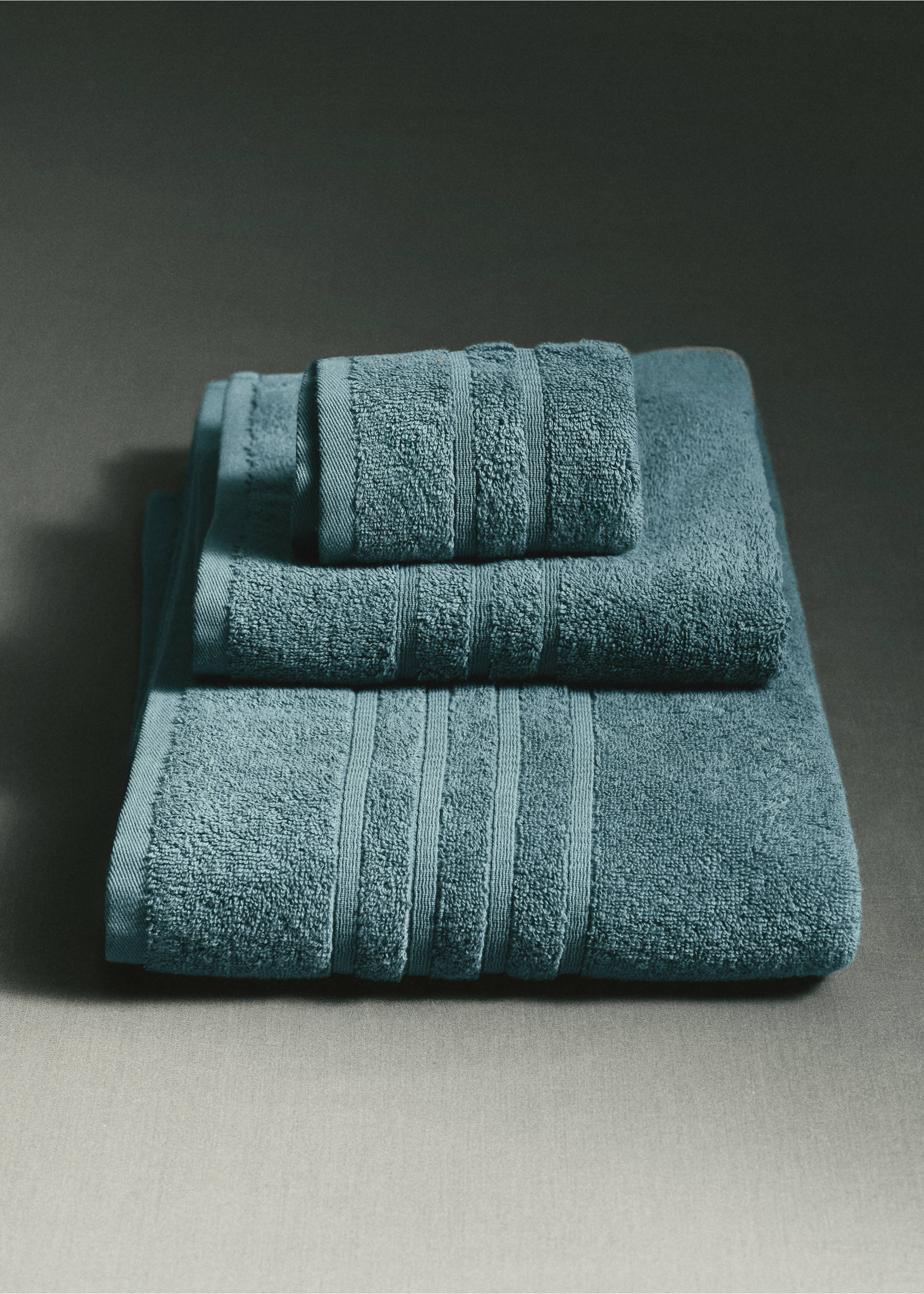 A stack of three teal towels featuring ribbed border details., Petrol Blue. Ref: 37002989-00.