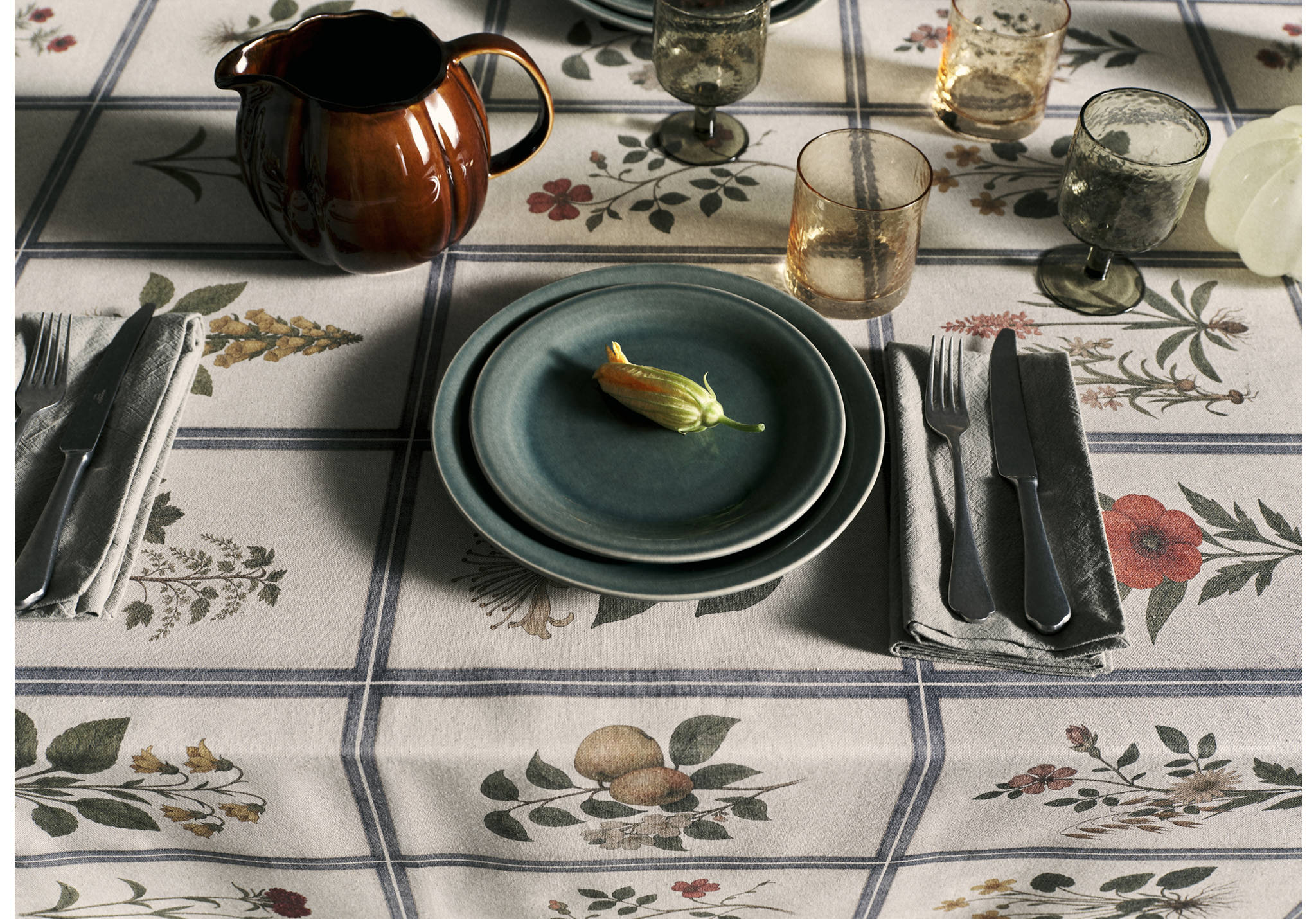 Dark green ceramic plates set on a botanical-print tablecloth.