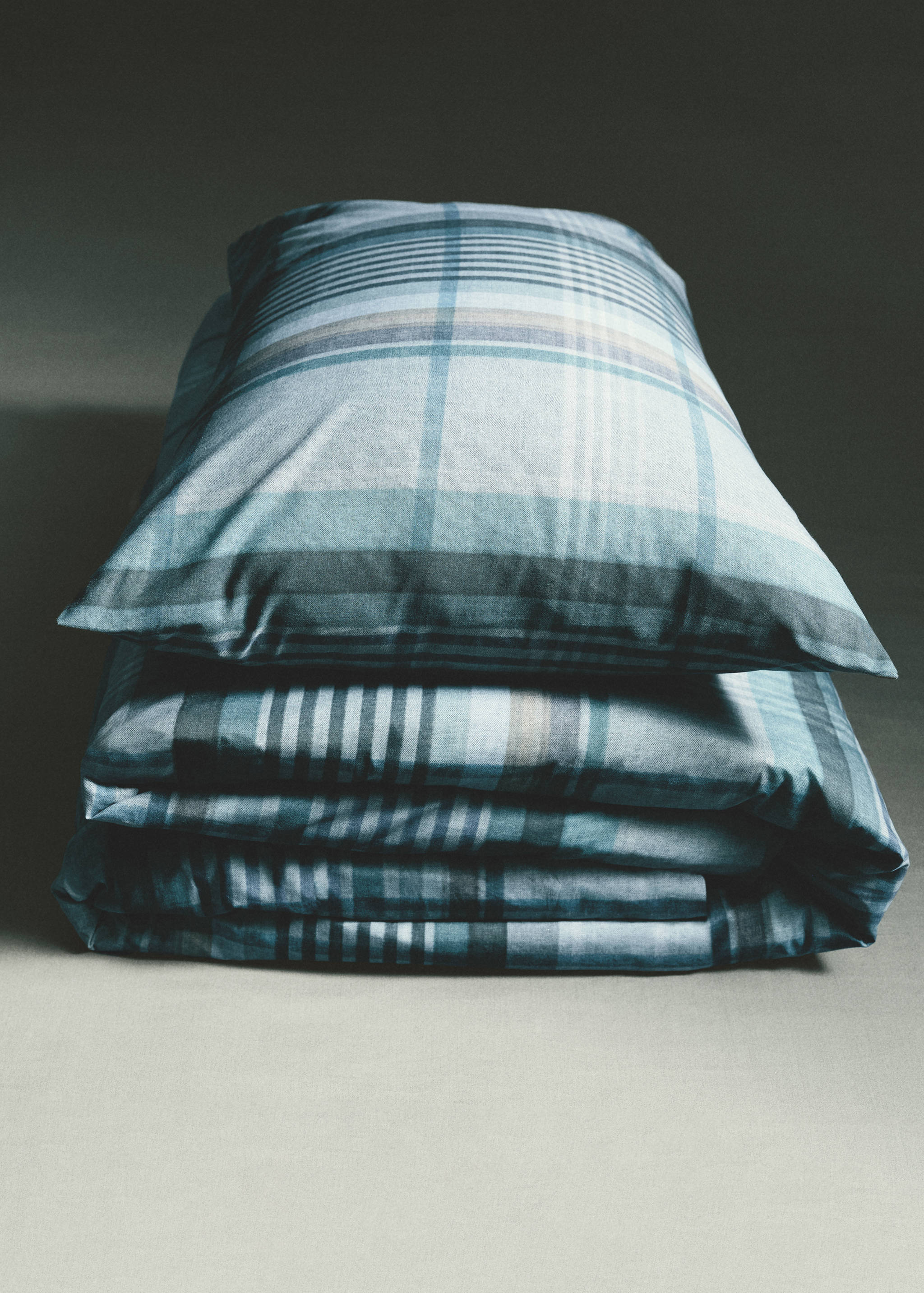Blue plaid duvet cover with matching pillows on a made bed.