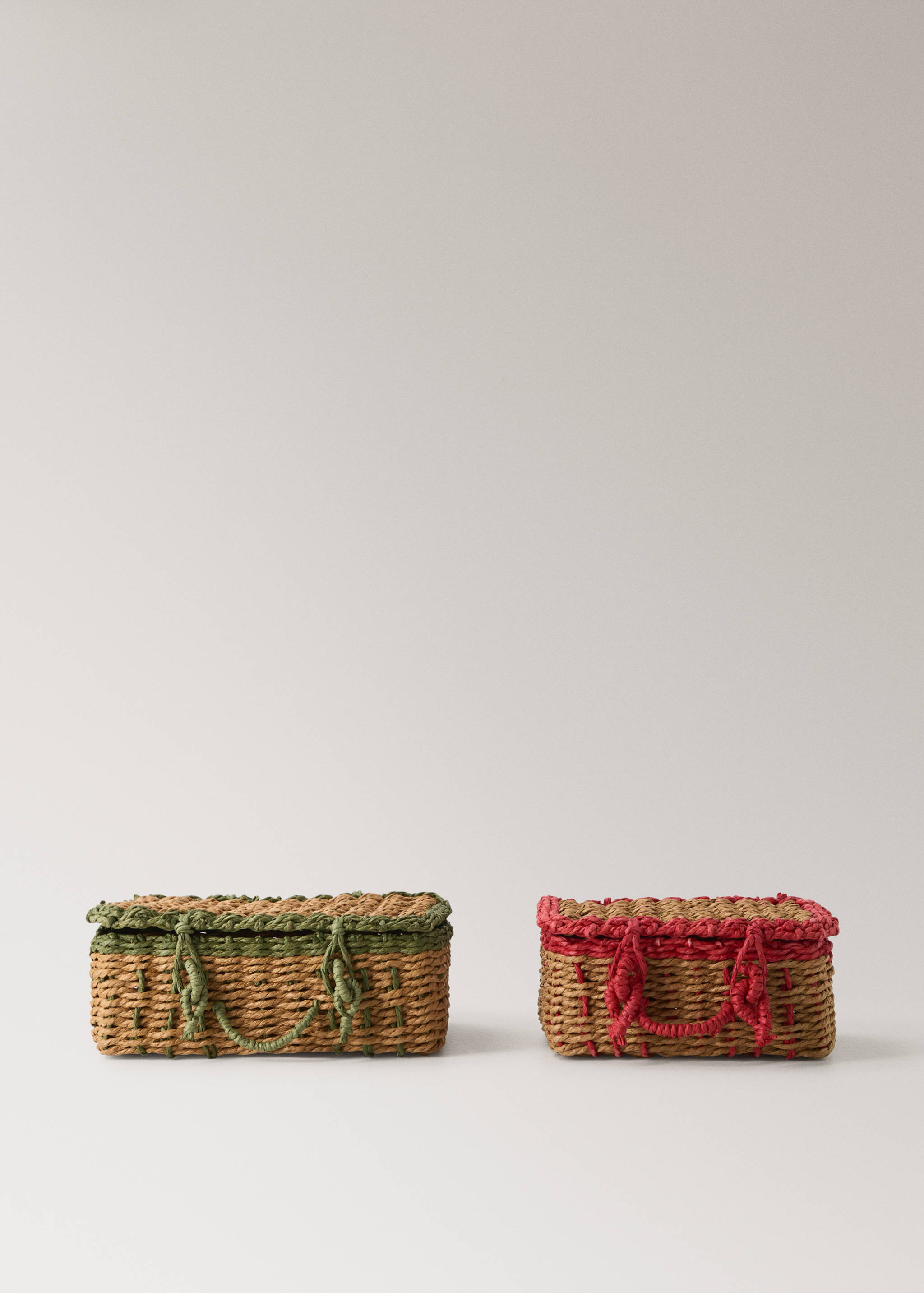 Two rectangular woven straw baskets with lids, one with green trim and handles and the other with pink trim and handles.