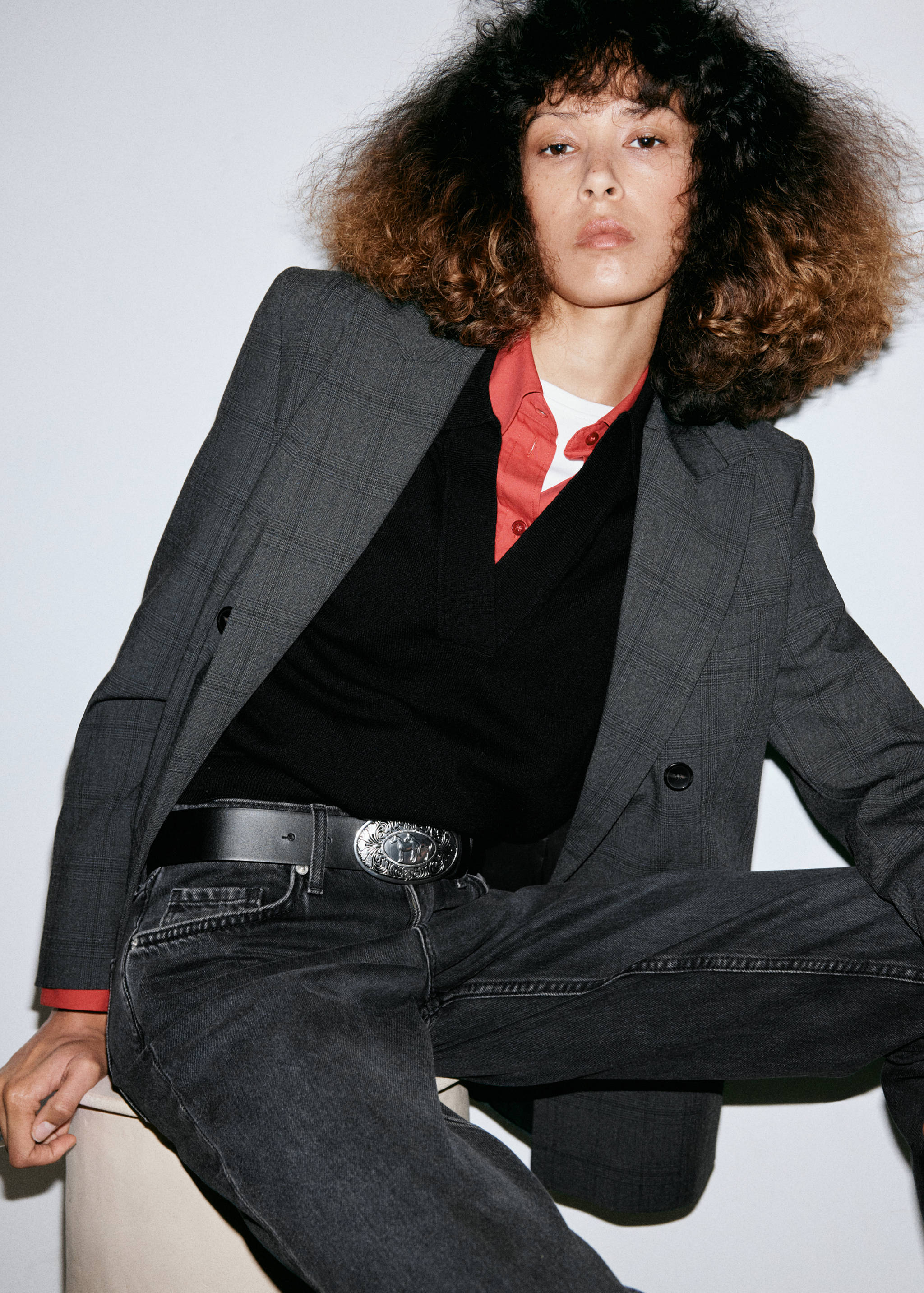 Dark grey wash denim jeans worn with a black belt and layered blazer.