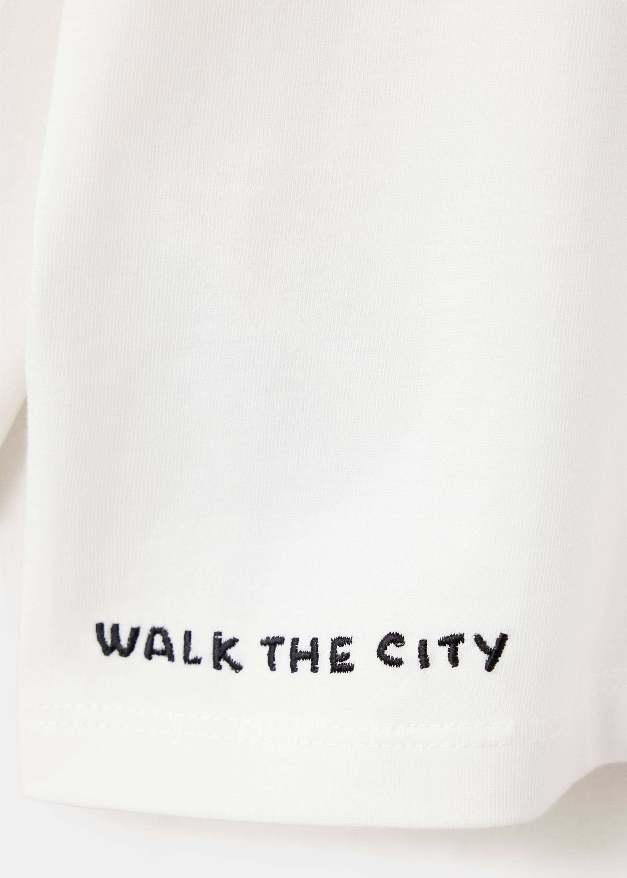 White kids' t-shirt fabric detail with black embroidered text.