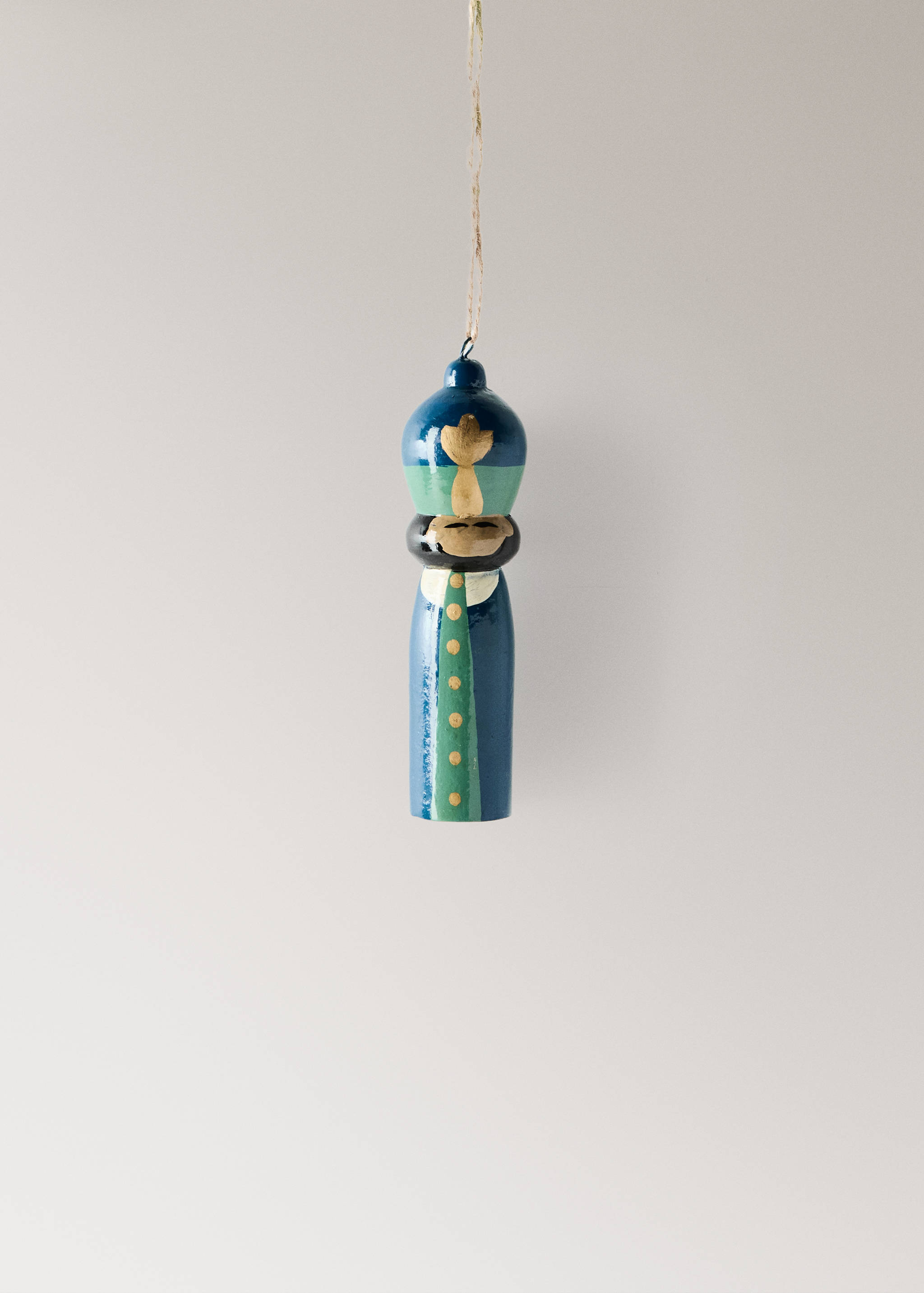 Blue and green wooden nutcracker Christmas ornament hanging from a twine string.