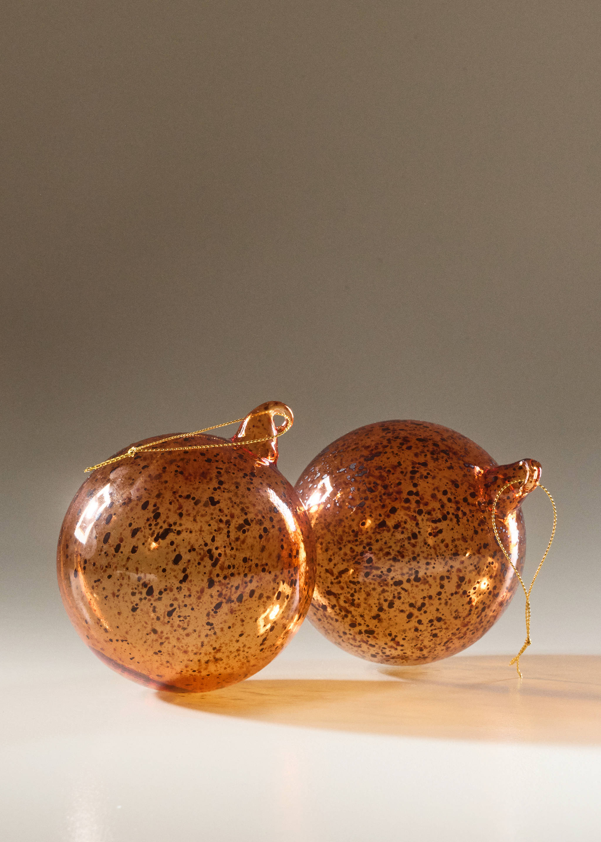 Amber speckled glass Christmas ornaments with gold hanging cords.