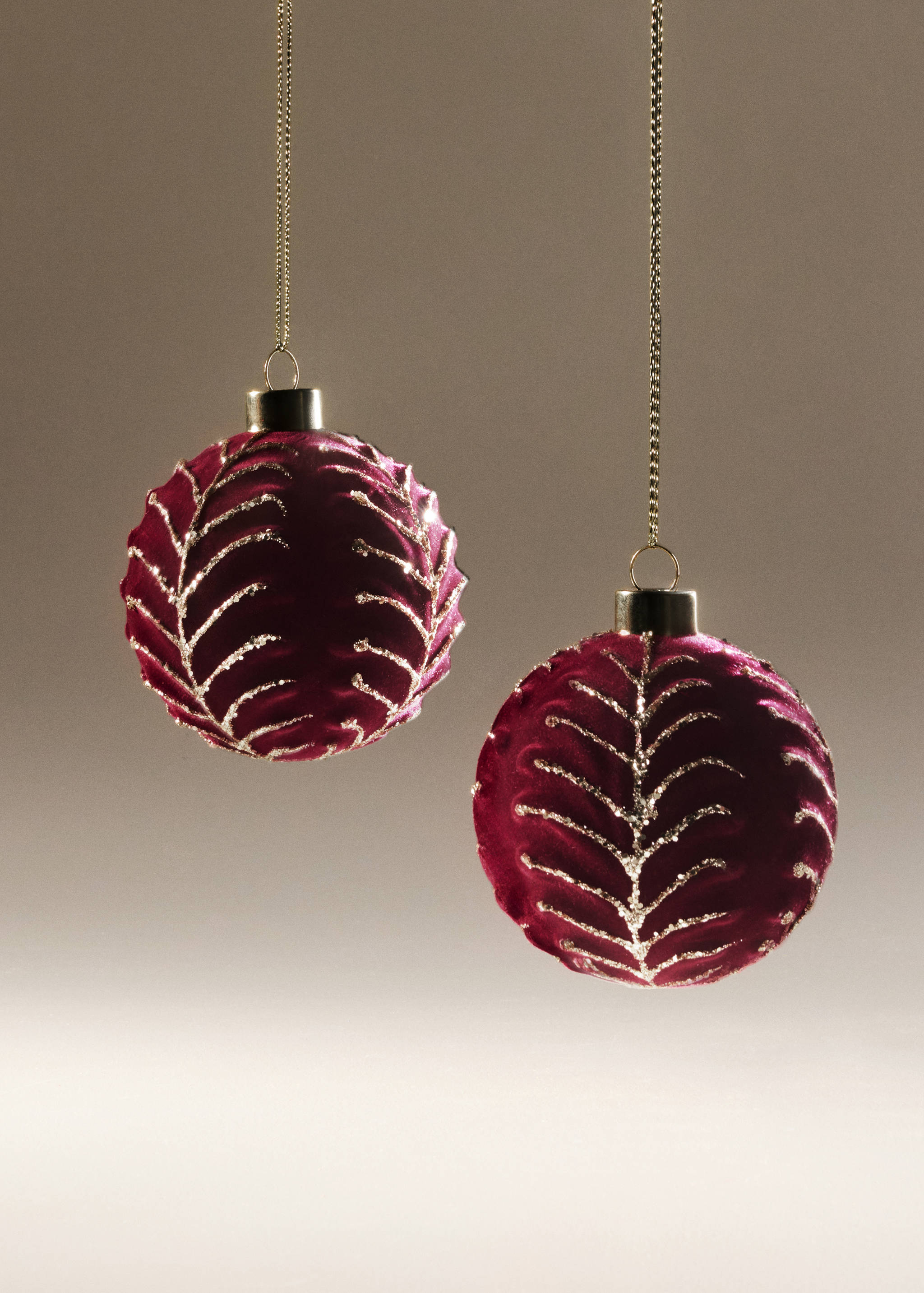 Dark red velvet Christmas baubles with a glittery leaf pattern.