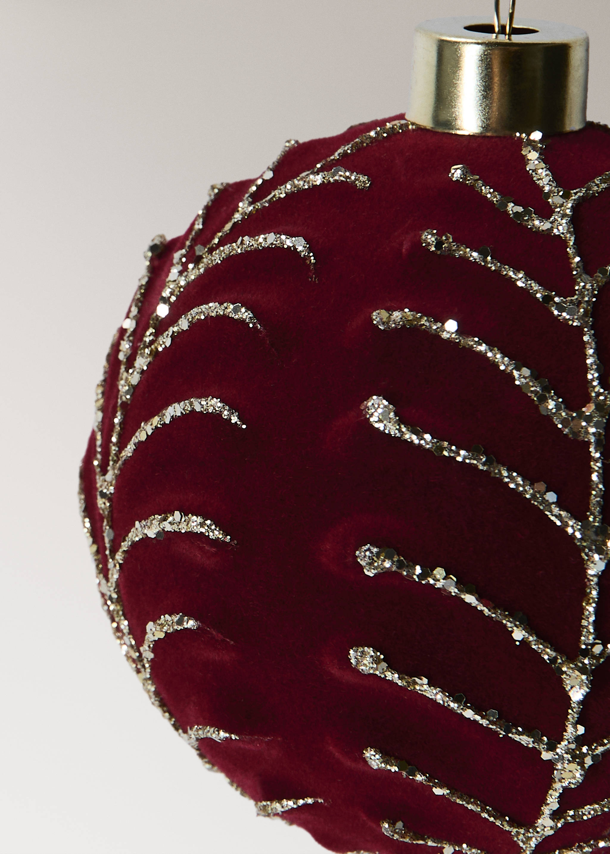 Burgundy velvet Christmas ornament with gold glitter branch patterns and a gold cap.