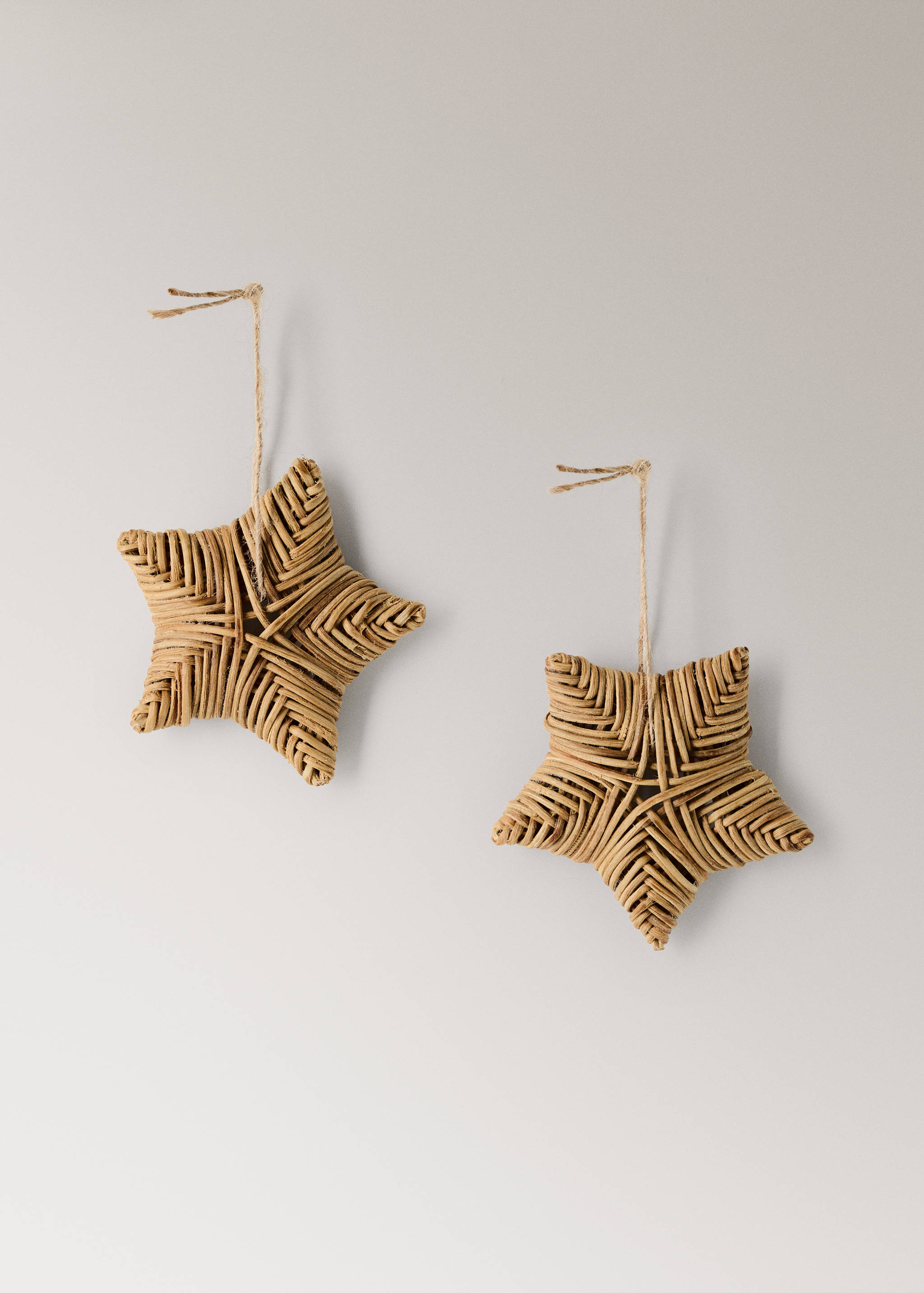 Two woven natural rattan star Christmas decorations with twine hanging loops.