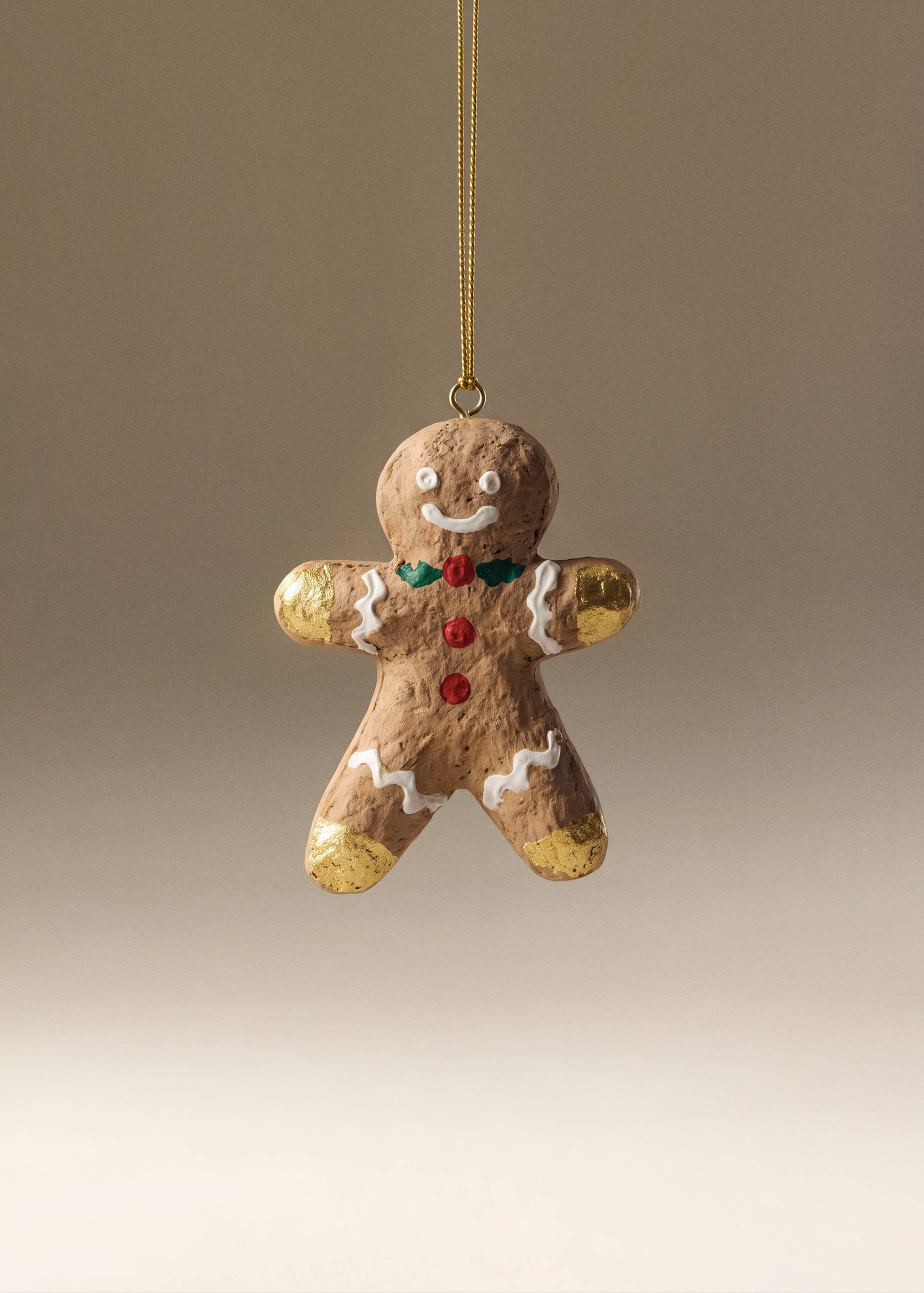 Brown gingerbread man Christmas ornament with icing details and gold accents.