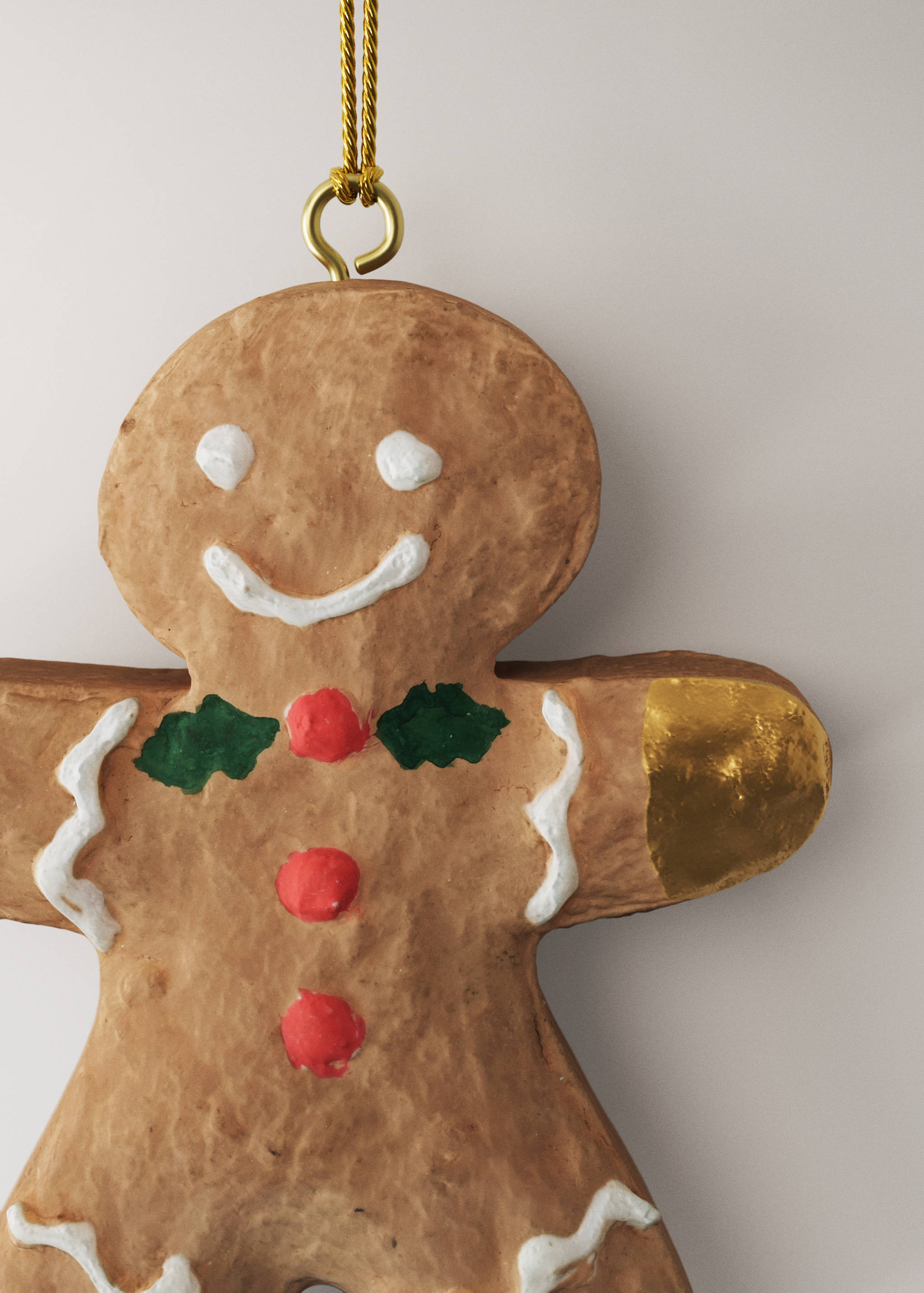 Textured gingerbread man Christmas ornament with painted white icing, red buttons, and gold details.