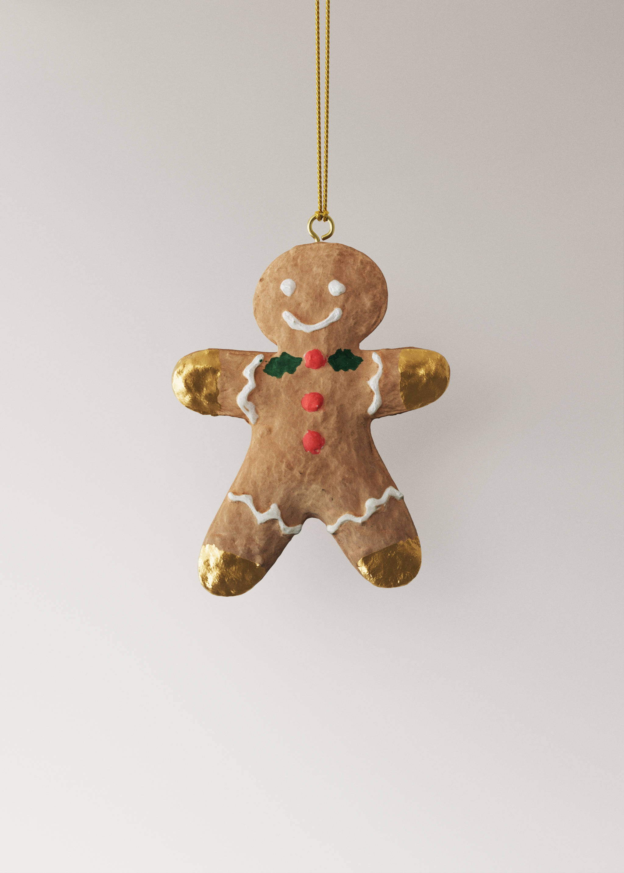 Brown textured gingerbread man Christmas ornament with painted icing and gold details, hanging on a gold string.