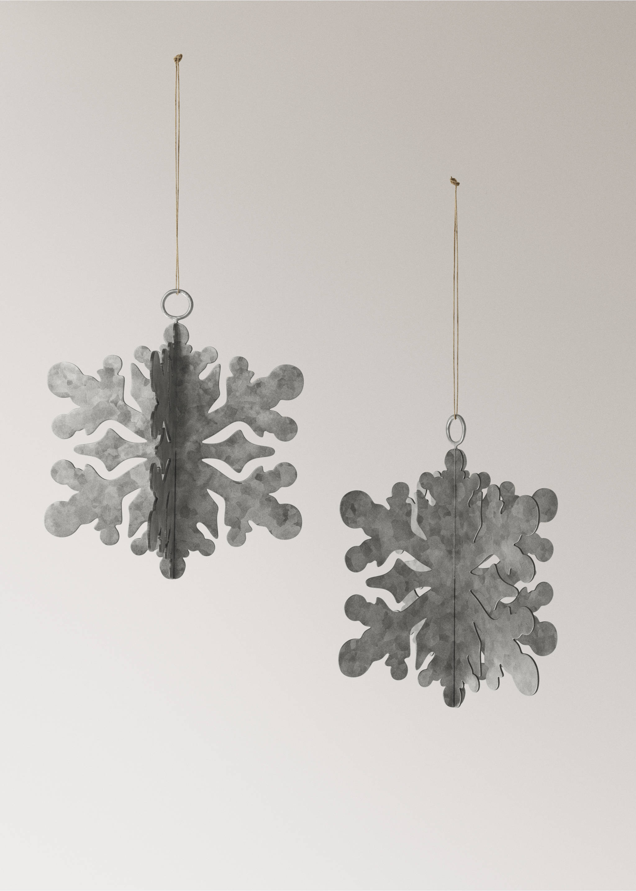 Two grey metallic snowflake Christmas ornaments hanging against a plain background., Silver. Ref: 37006782-00.