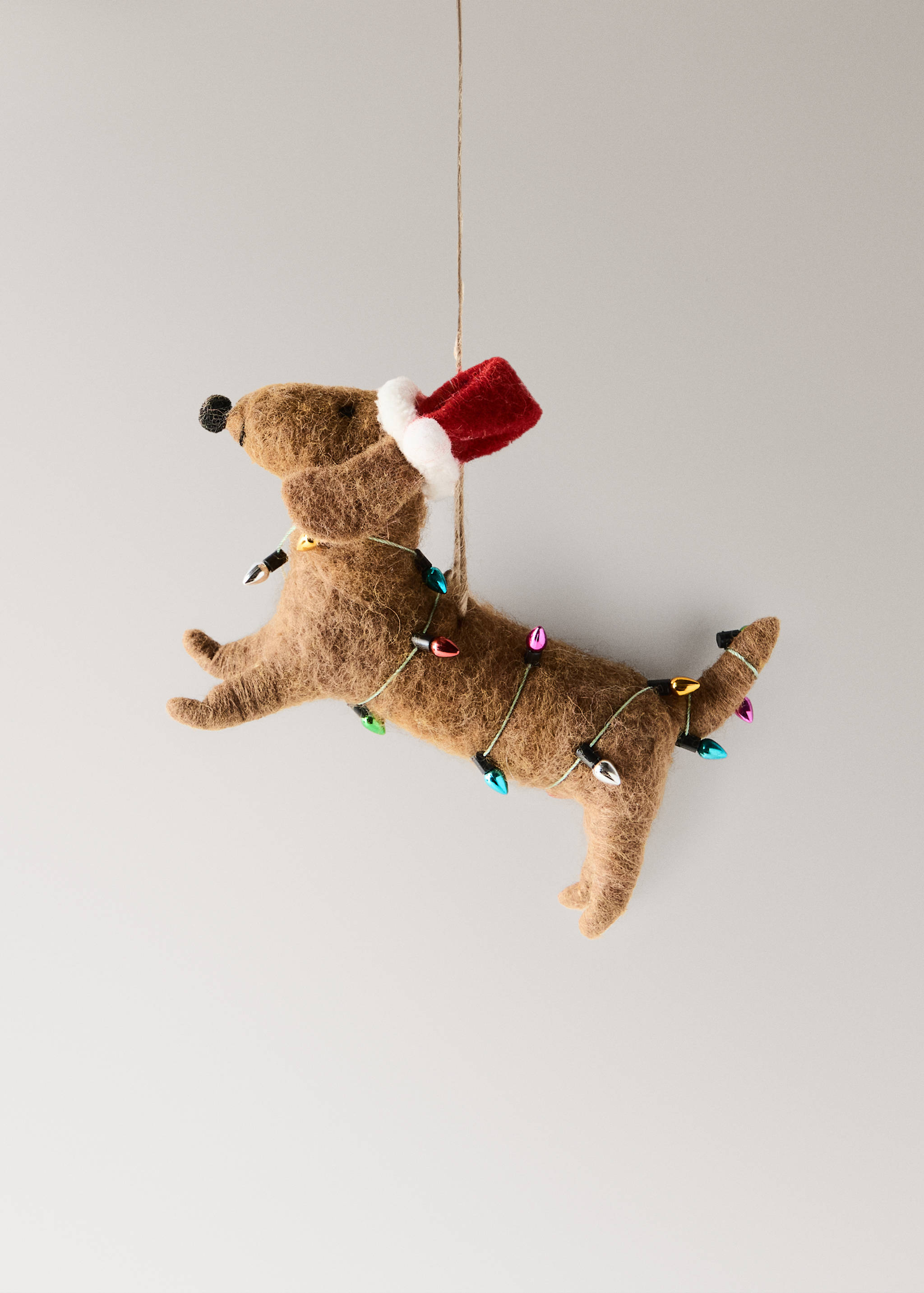 Brown felt dachshund Christmas ornament wearing a red hat and colorful fairy lights.