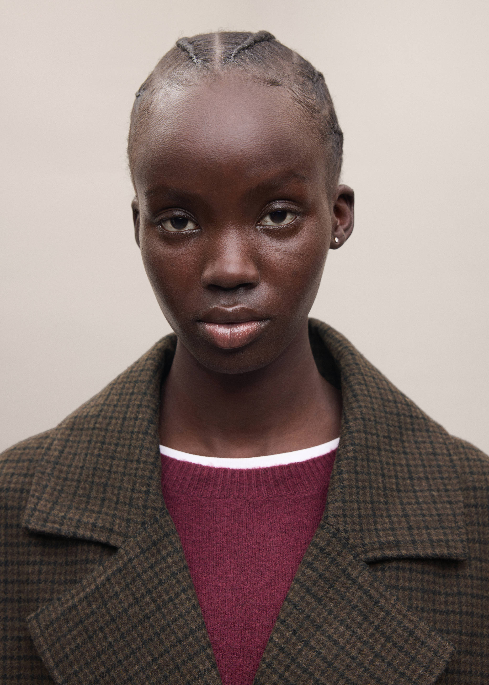 Close-up of a brown patterned coat with wide lapels, worn over a burgundy jumper.