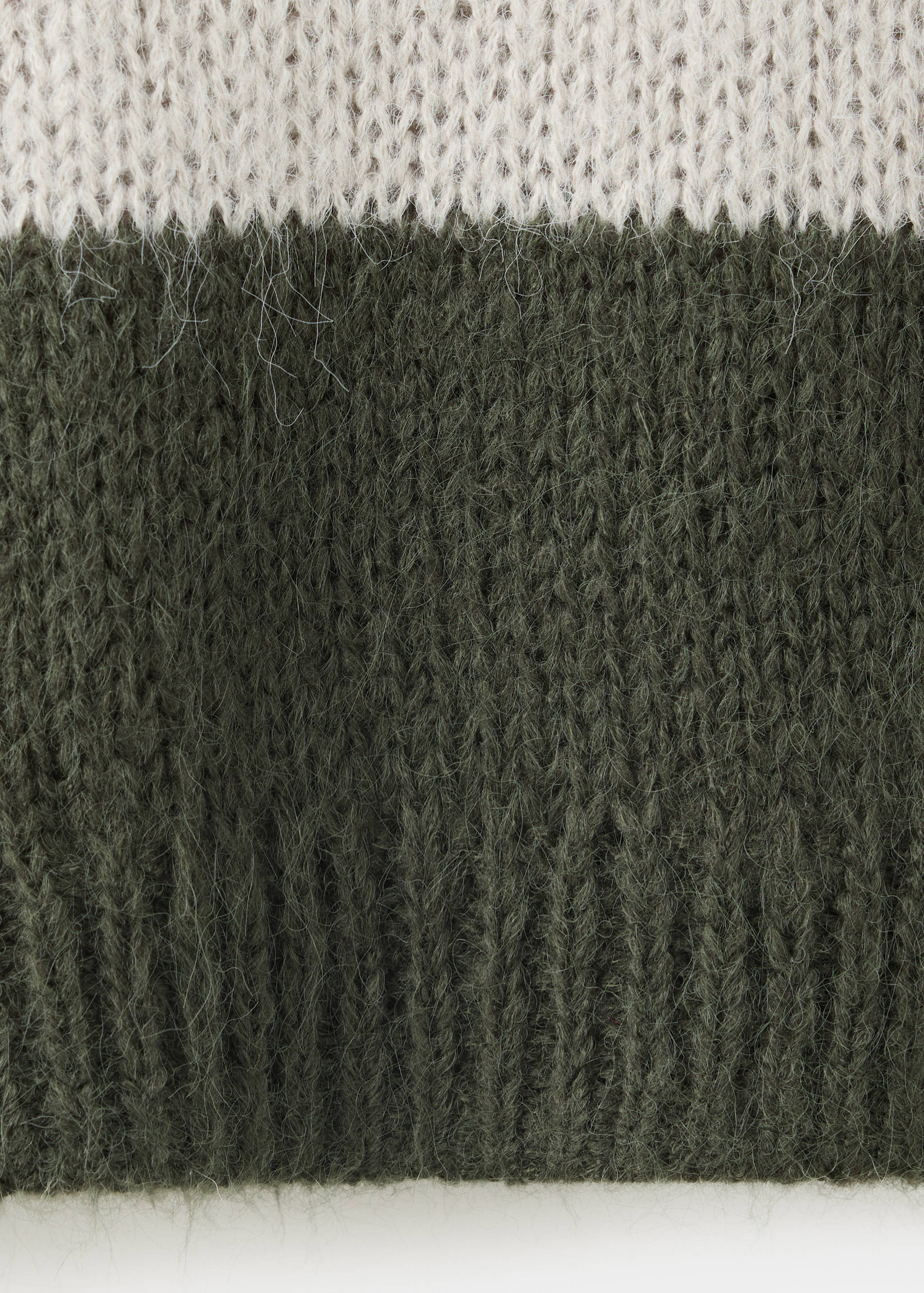 Close-up of a fuzzy ribbed-knit jersey in cream and dark green.