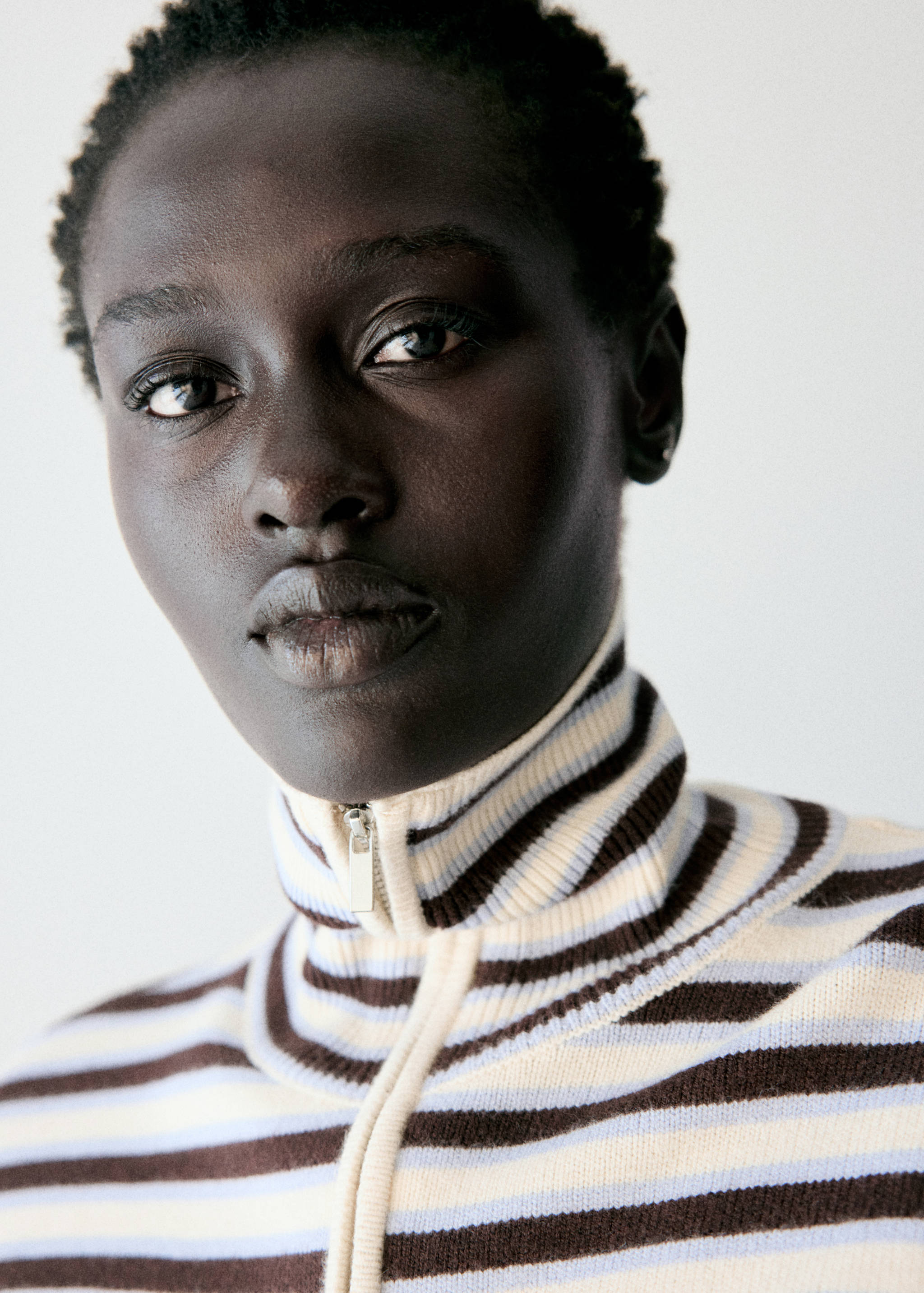 Close-up of a striped knitted jumper with a high zip-up collar.