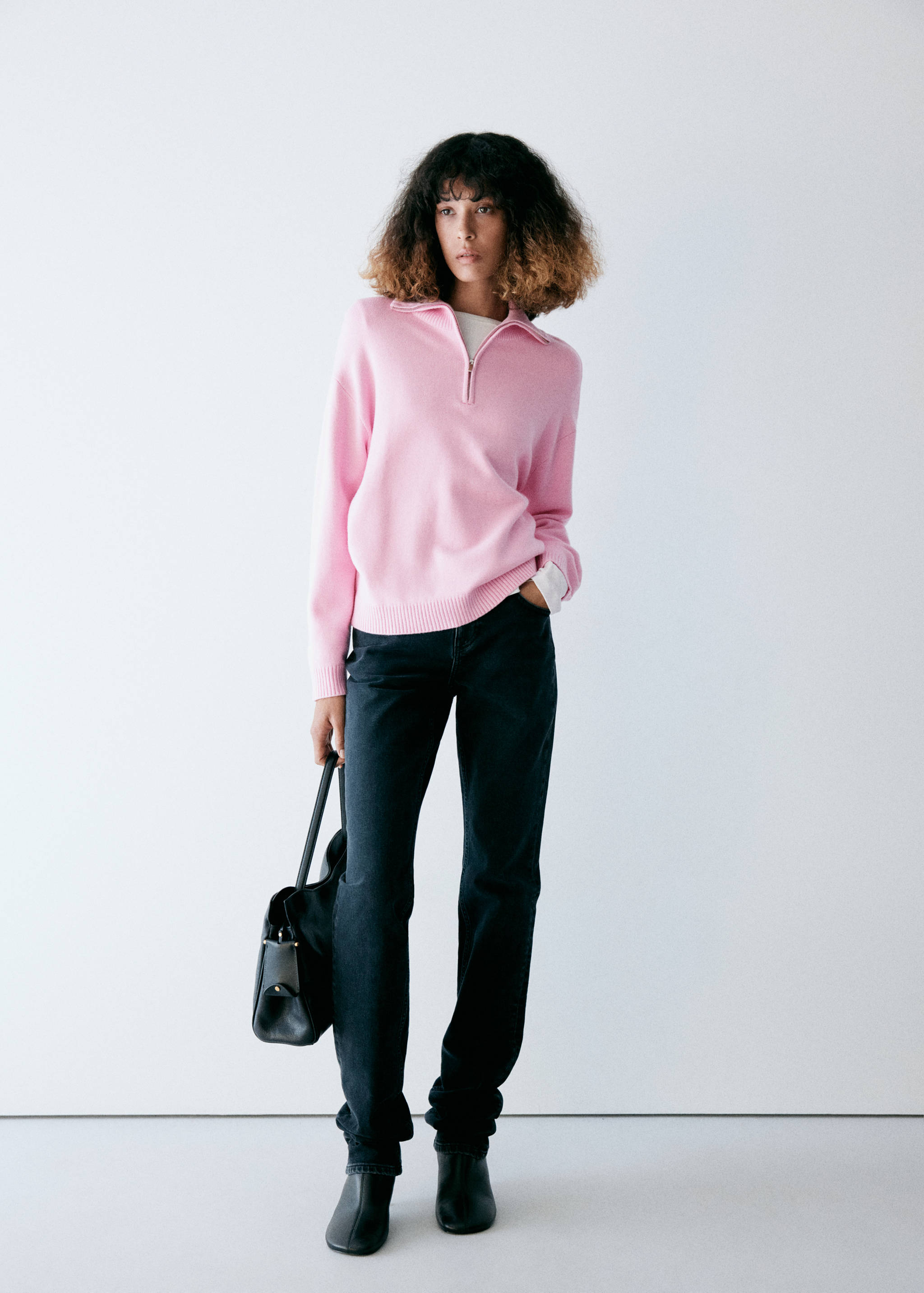 Pink zip-neck jersey worn with dark trousers and a black bag.