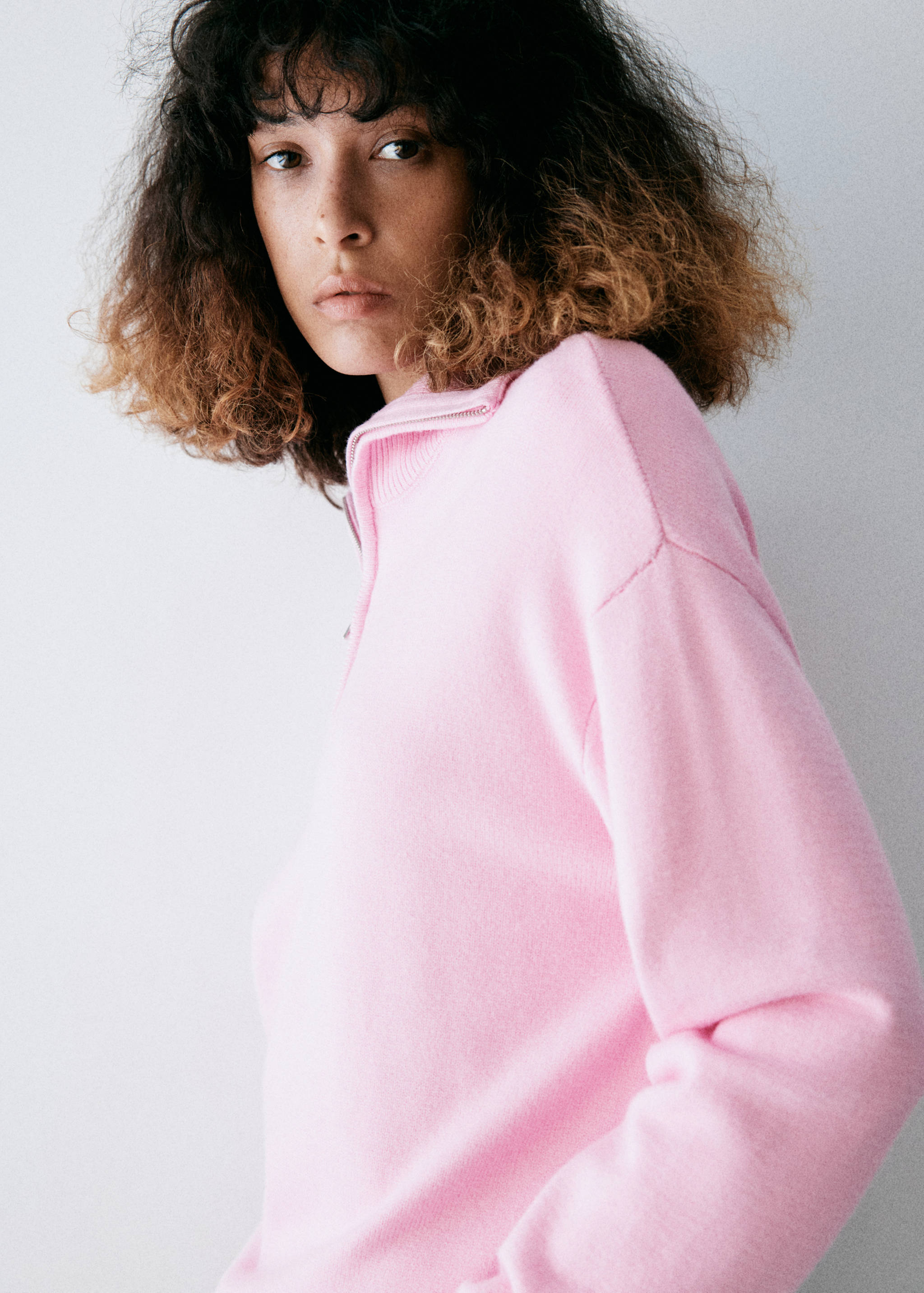 Pink knit jumper with a high zip-up collar and long sleeves.