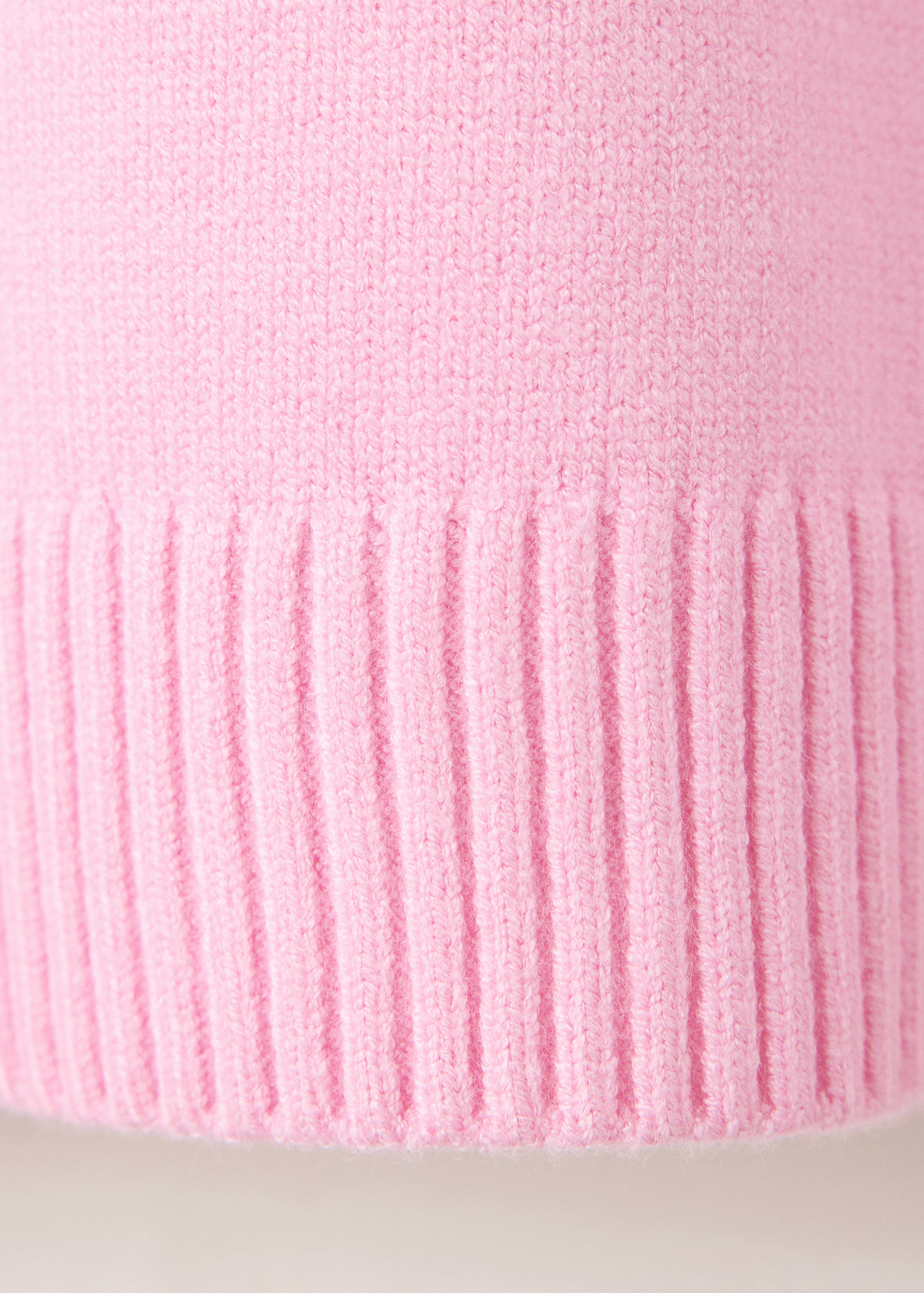 Close-up of pink jersey fabric showing fine knit and ribbed hem.