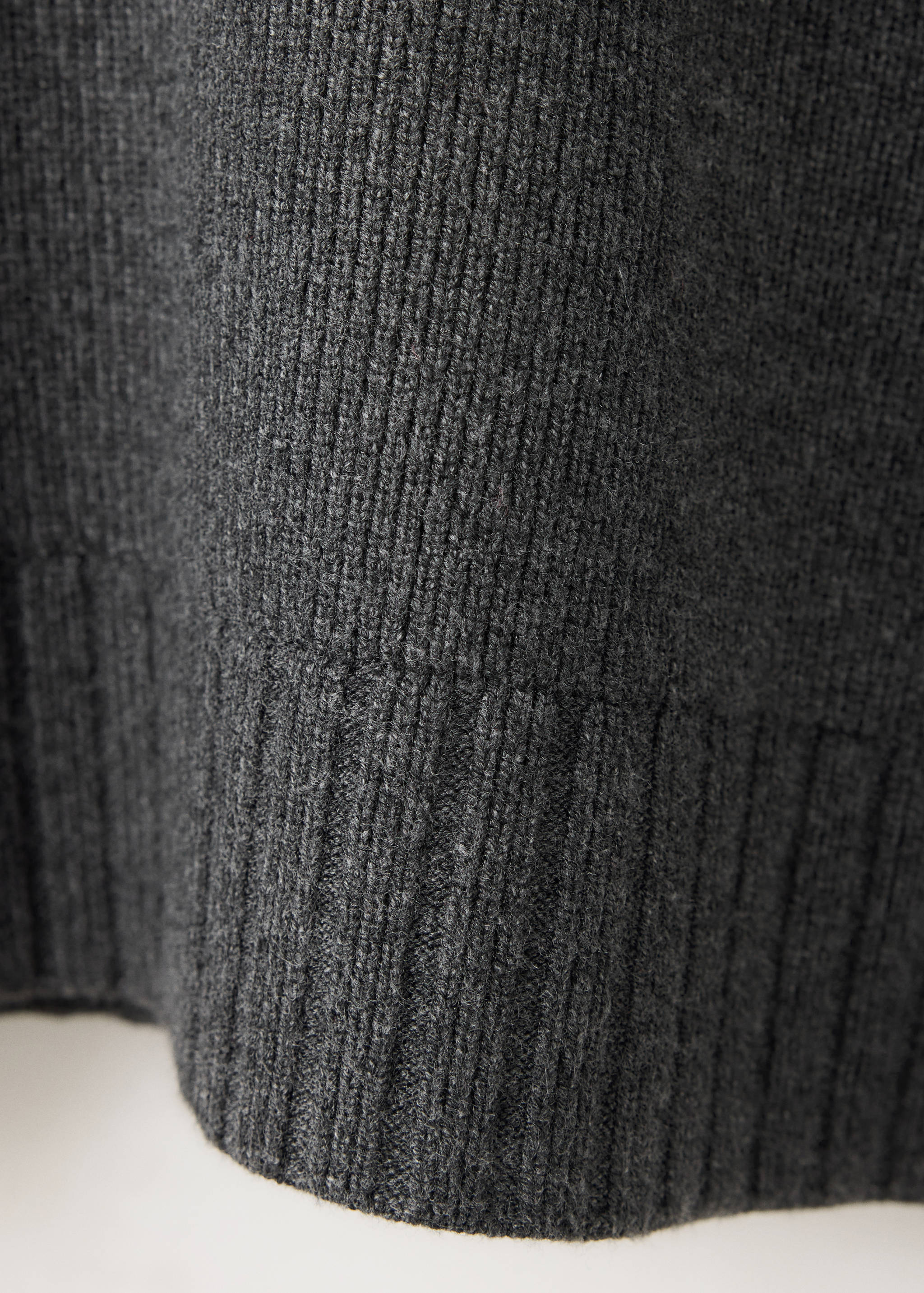Close-up of the dark grey ribbed knit texture of a sweater.