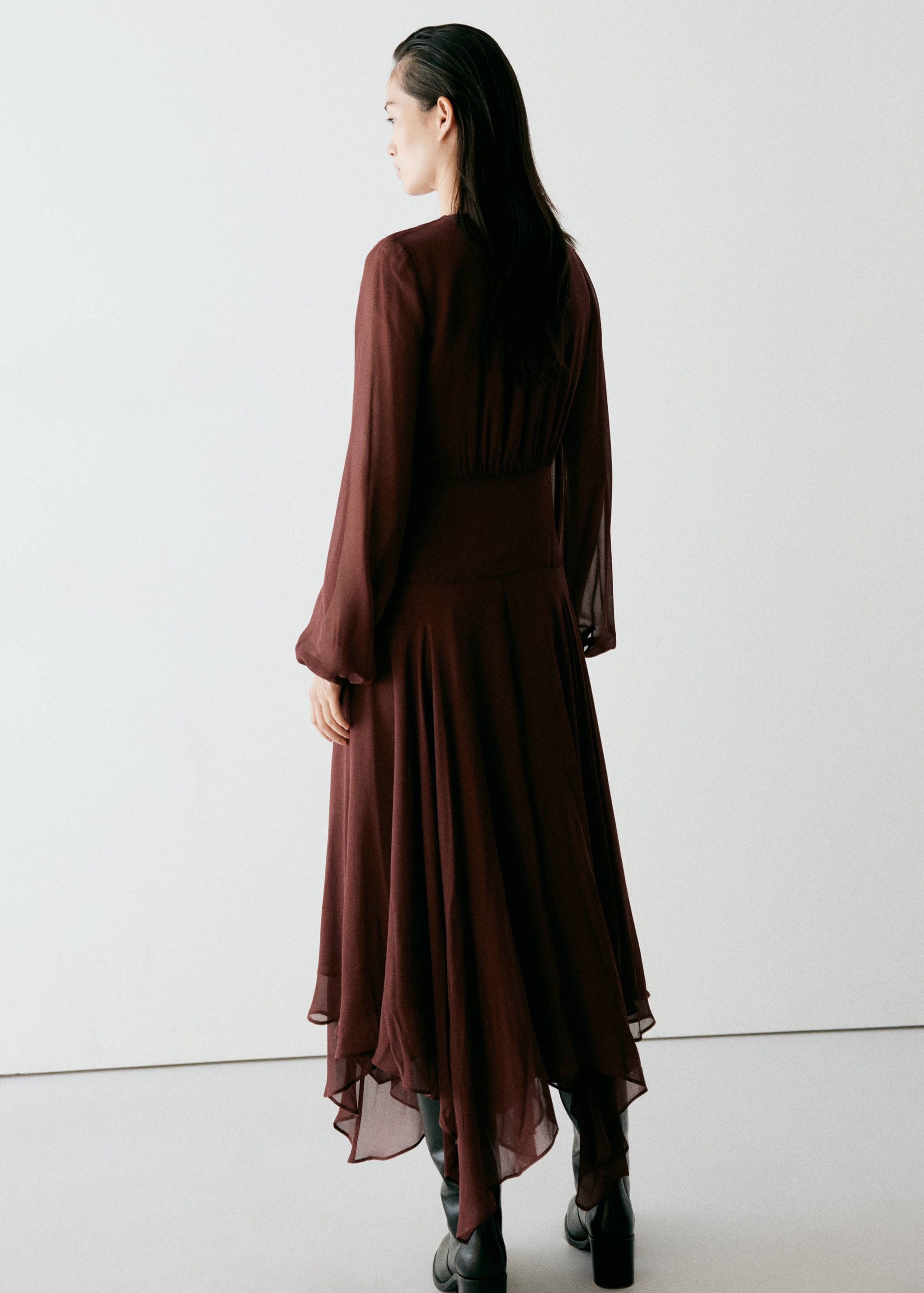 Dark brown long-sleeved midi dress with an asymmetric handkerchief hem, back view.