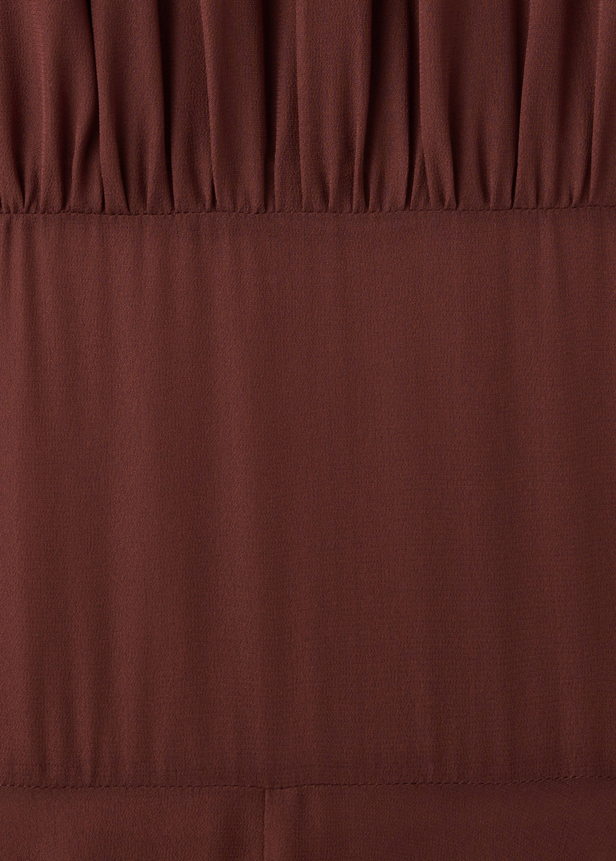 Brown dress detail showing gathered bodice and waist seam.