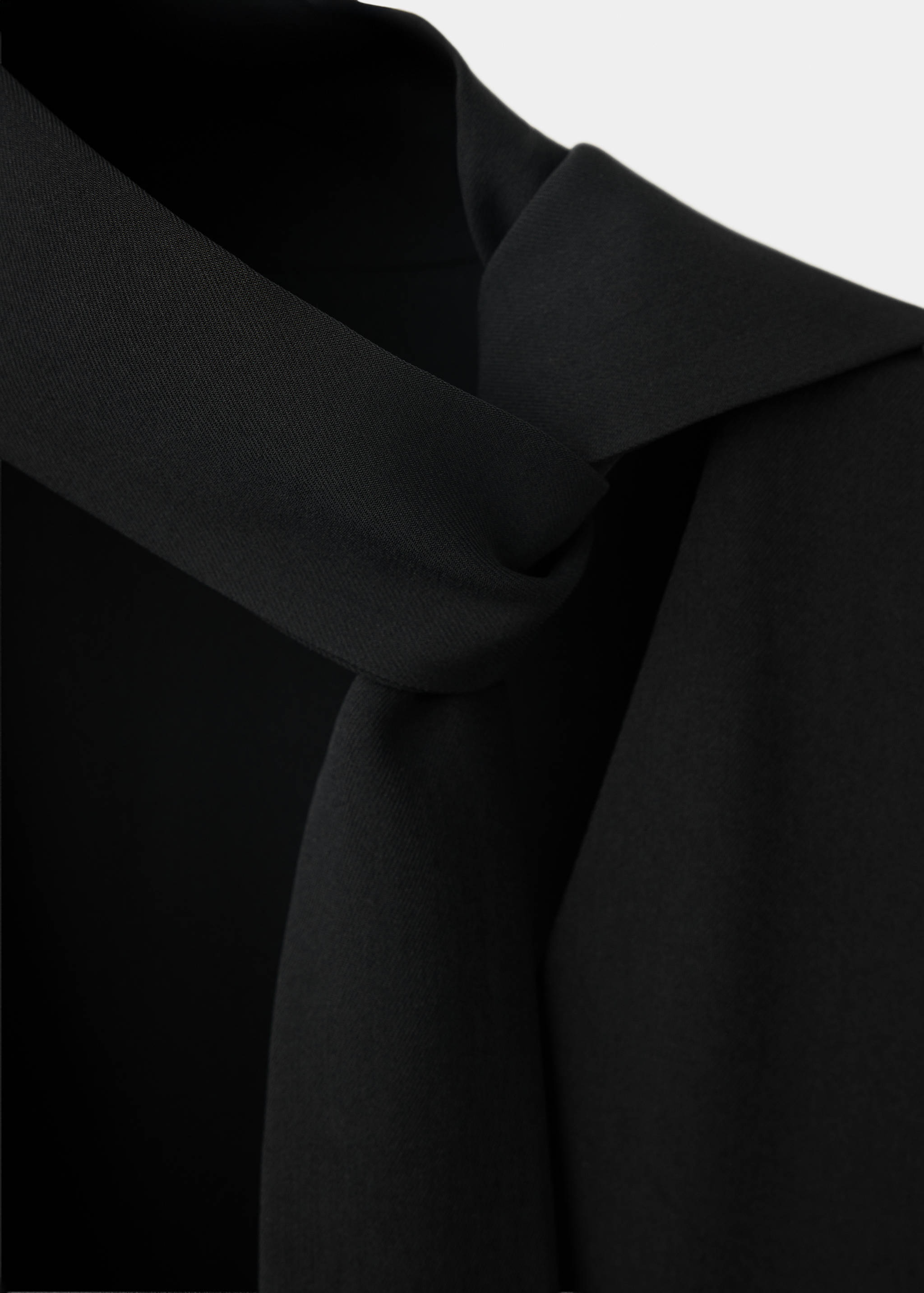Detalle de vestido negro que muestra el cuello drapeado.