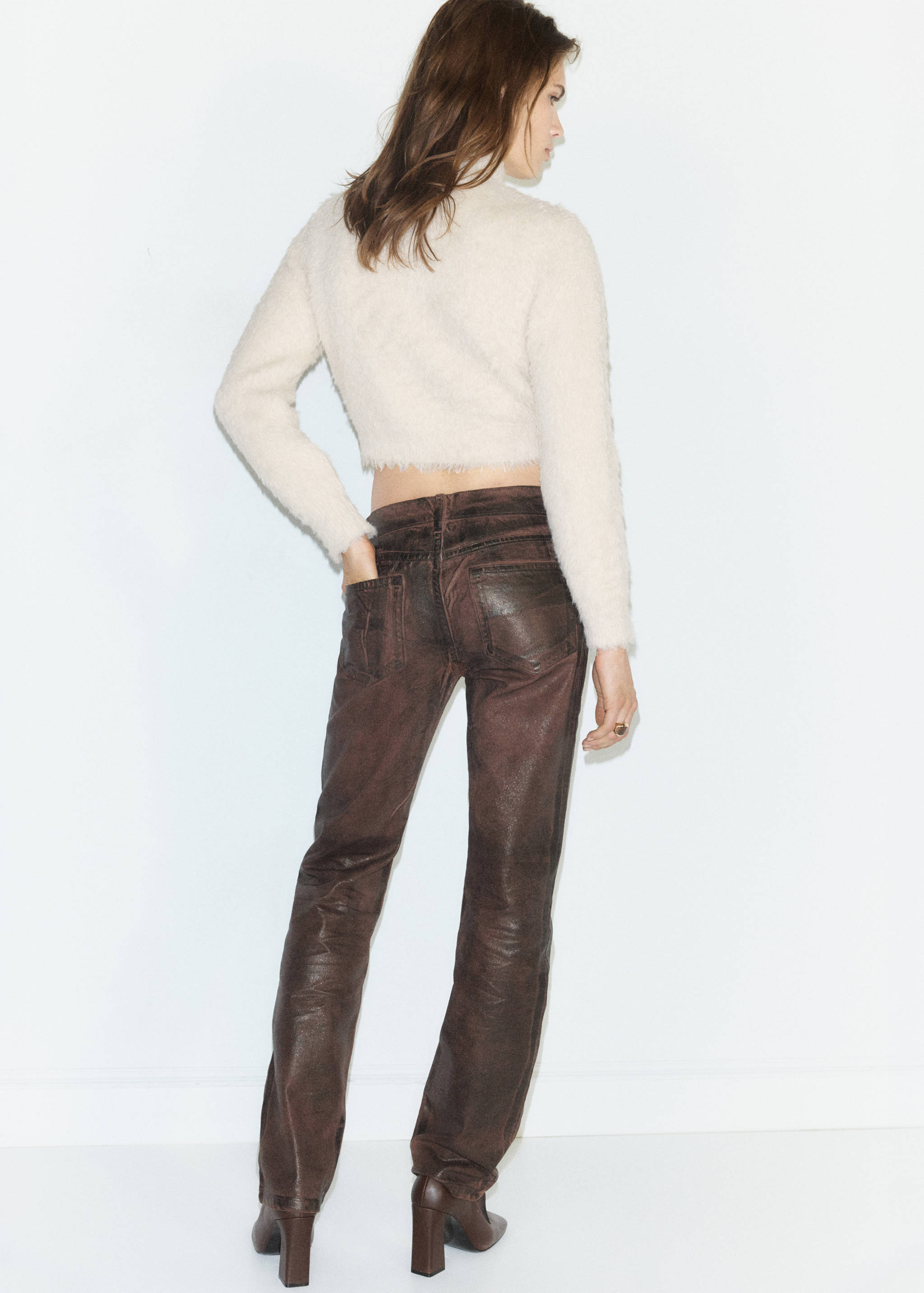 Back view of a light-coloured fuzzy cropped jersey worn with dark trousers.