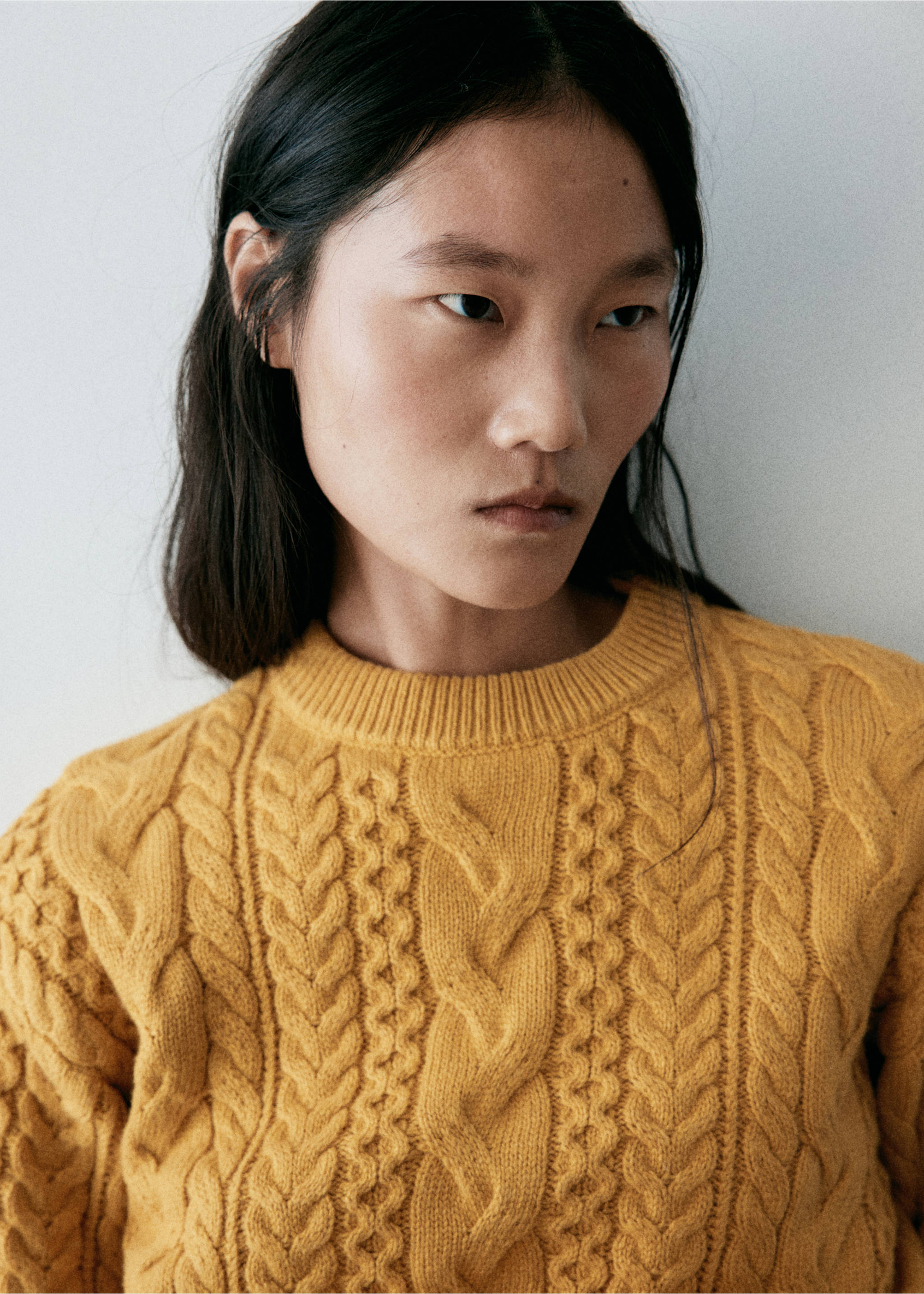 Mustard yellow cable-knit sweater with a ribbed round neck in a close-up model view., Mustard. Ref: 37007801-00.