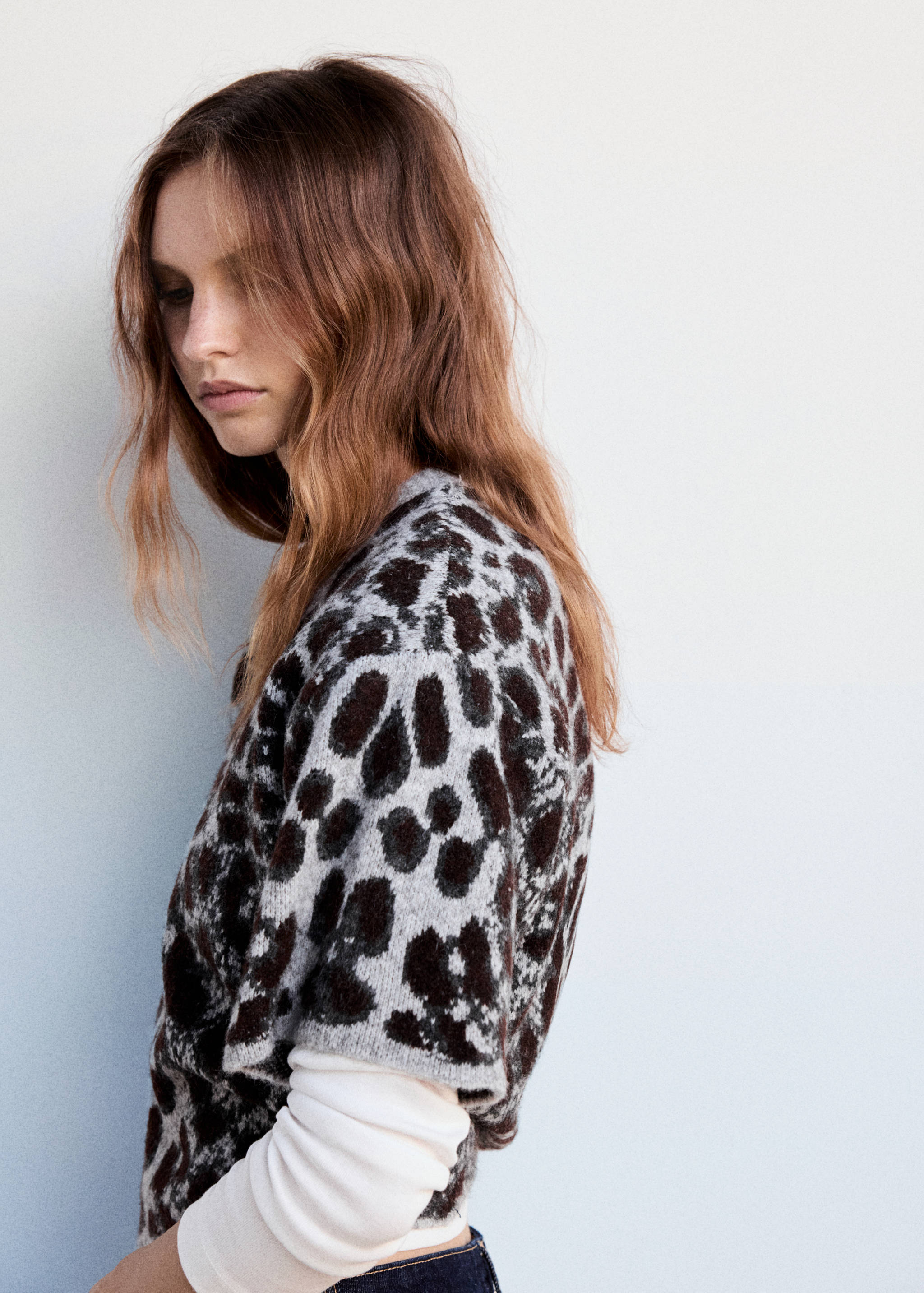 Close-up of a model wearing a short-sleeved animal print sweater over a white top.