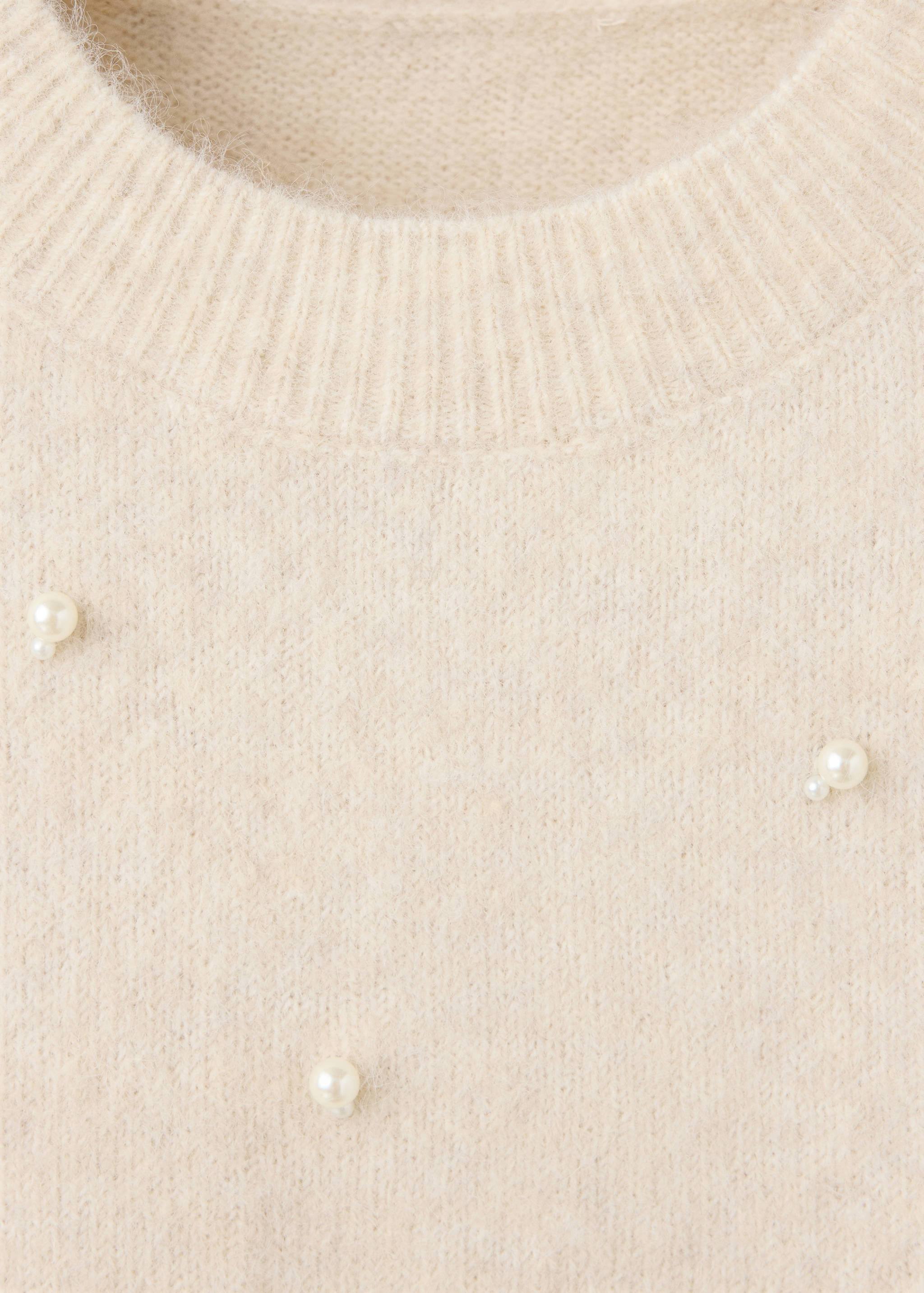 Cream knit sweater detail with crew neck and pearl beads.