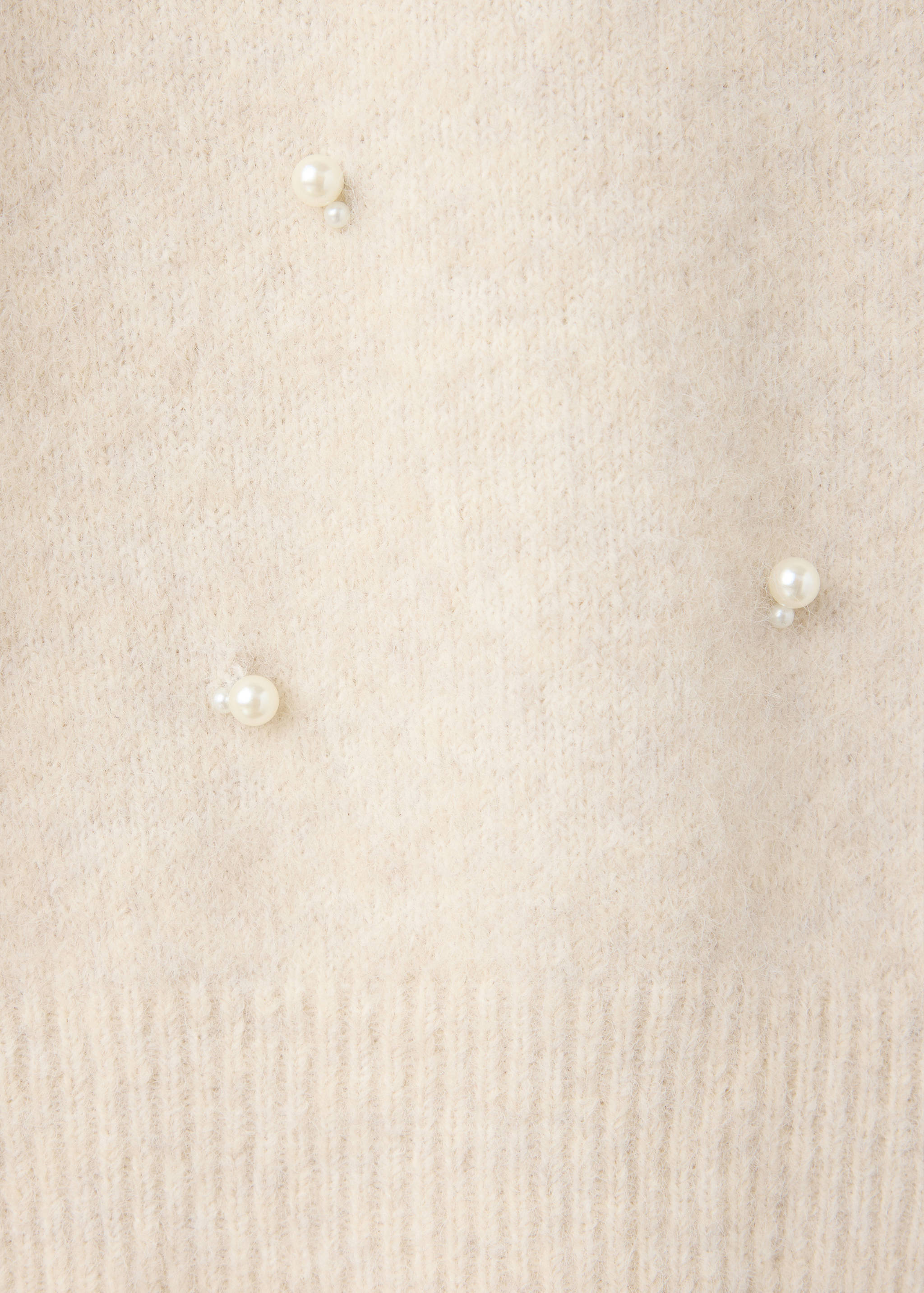 Close-up of a cream knit jersey with fuzzy texture and pearl bead details.