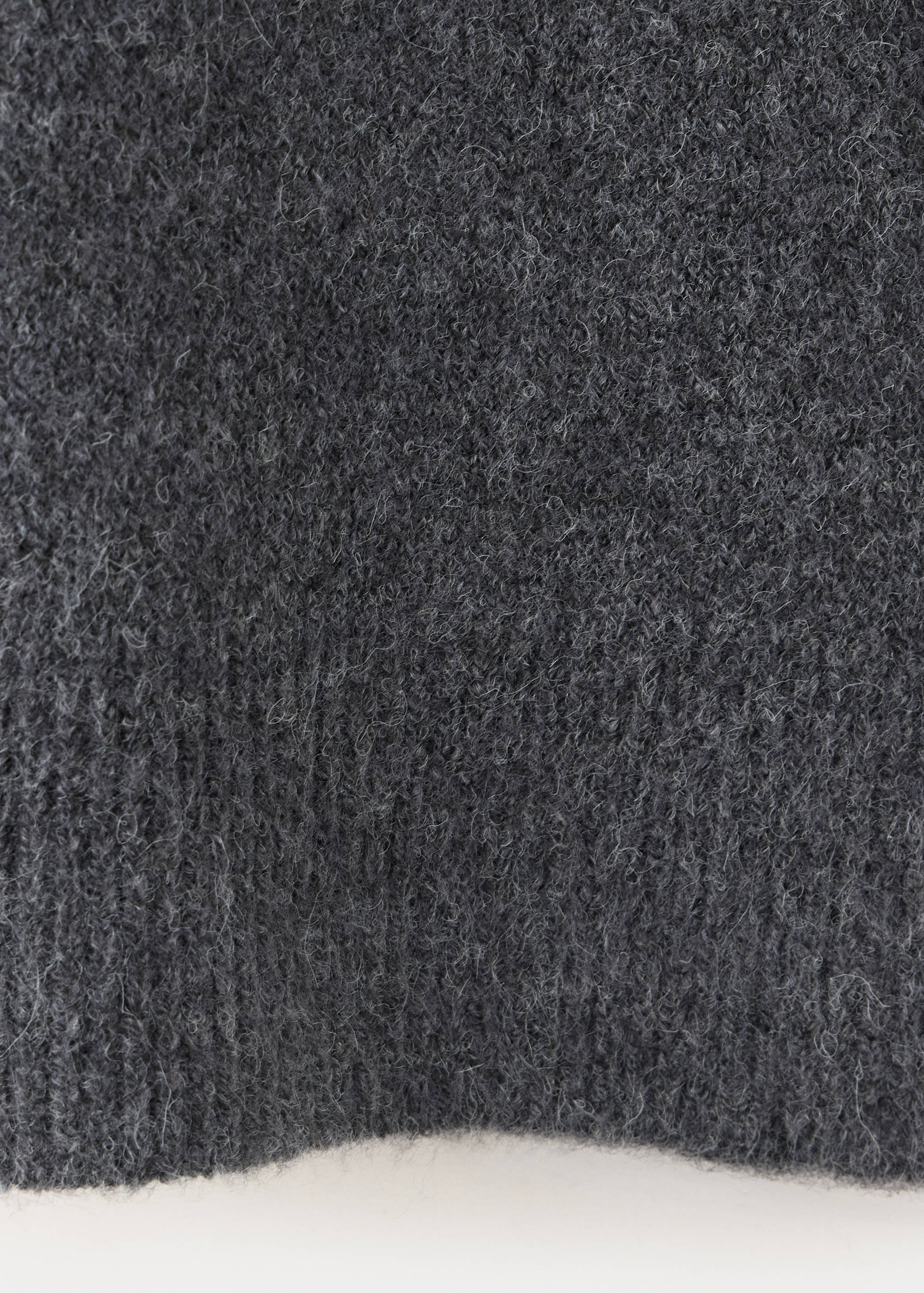 Close-up of the fuzzy dark grey knit texture of a jumper.