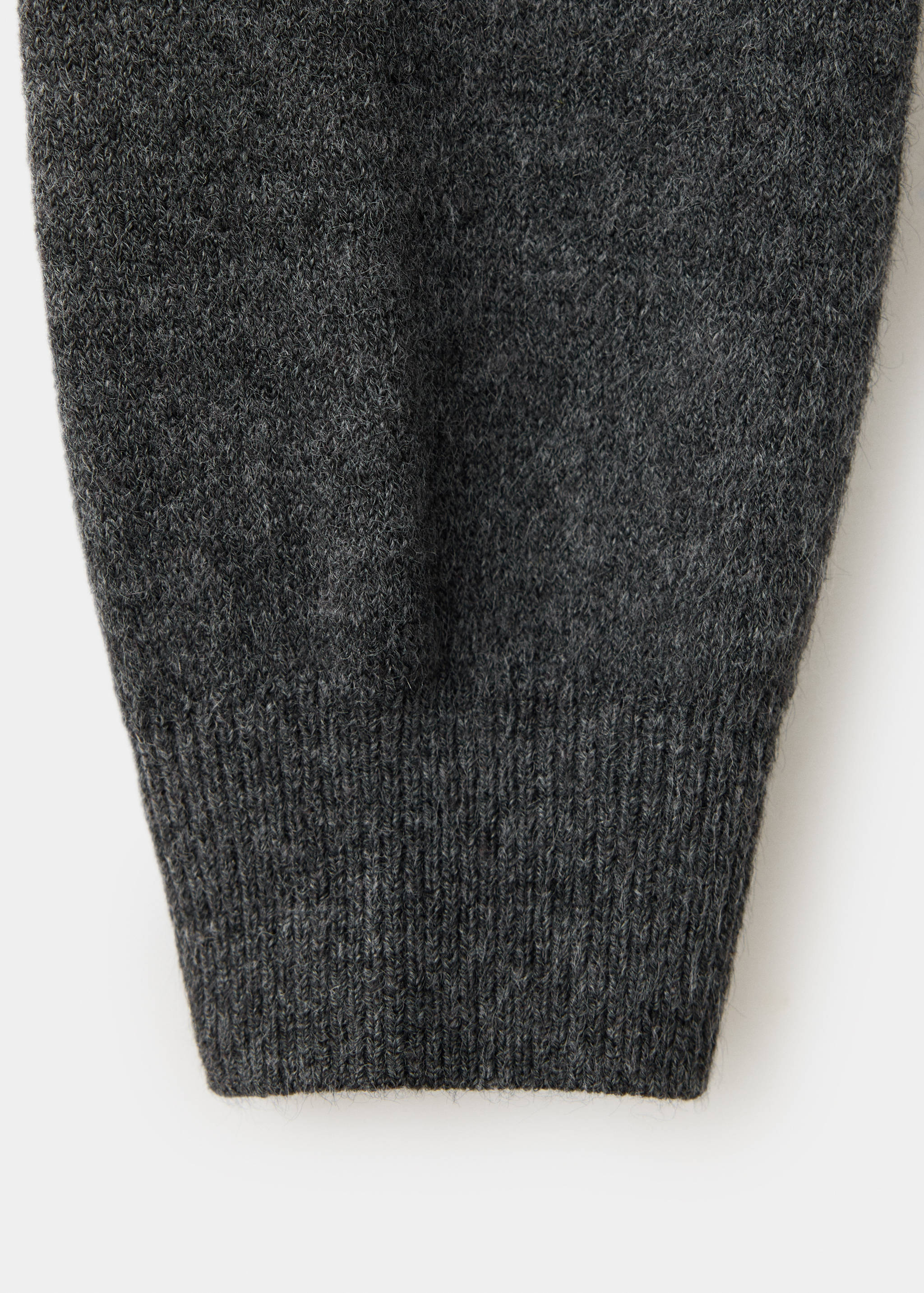 Close-up of a dark grey knitted sweater sleeve with a ribbed cuff.
