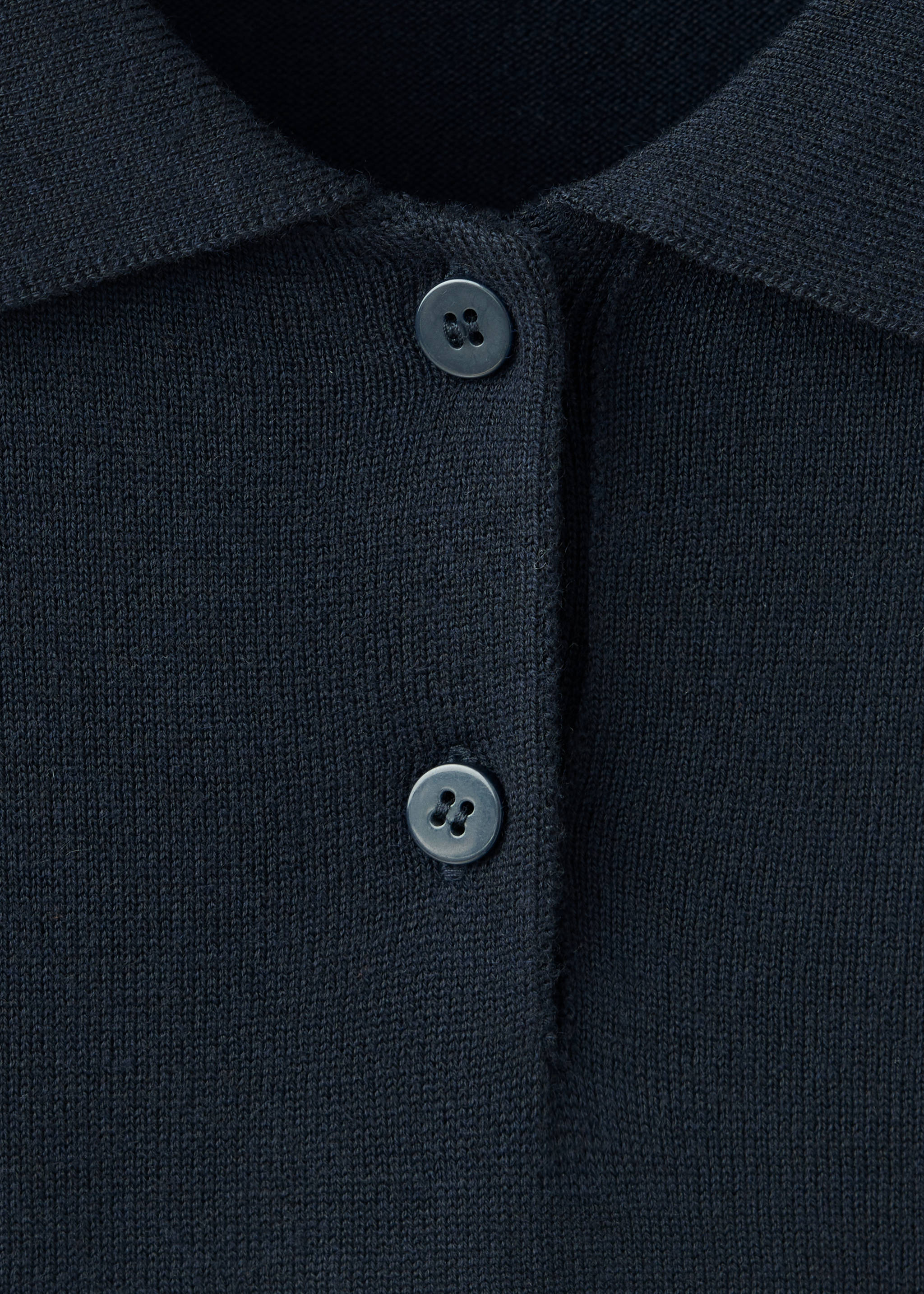 Close-up of a dark blue knitted jersey featuring a collar and two-button placket.
