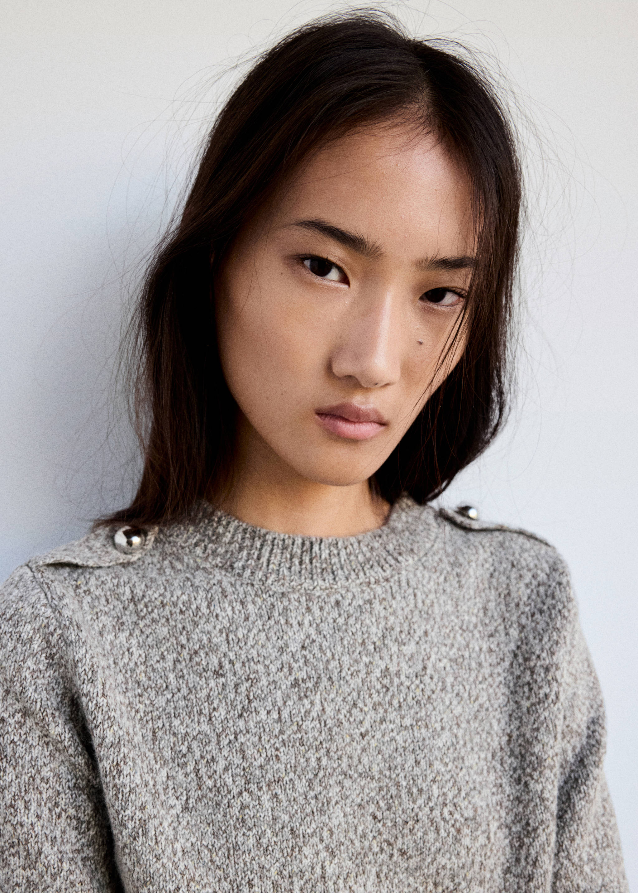 Grey marled knit jumper featuring a round neckline and shoulder buttons.