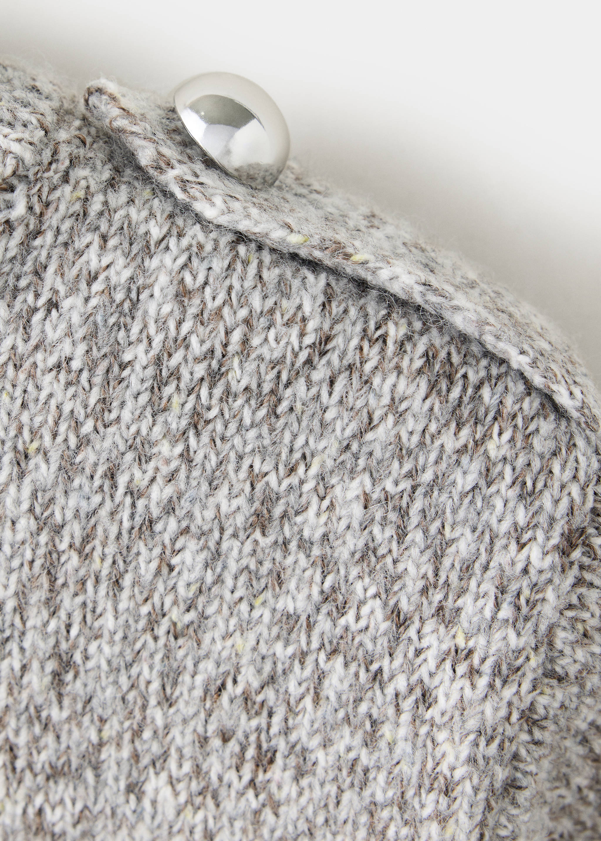 Close-up of a grey speckled knit jersey with a buttoned shoulder tab.