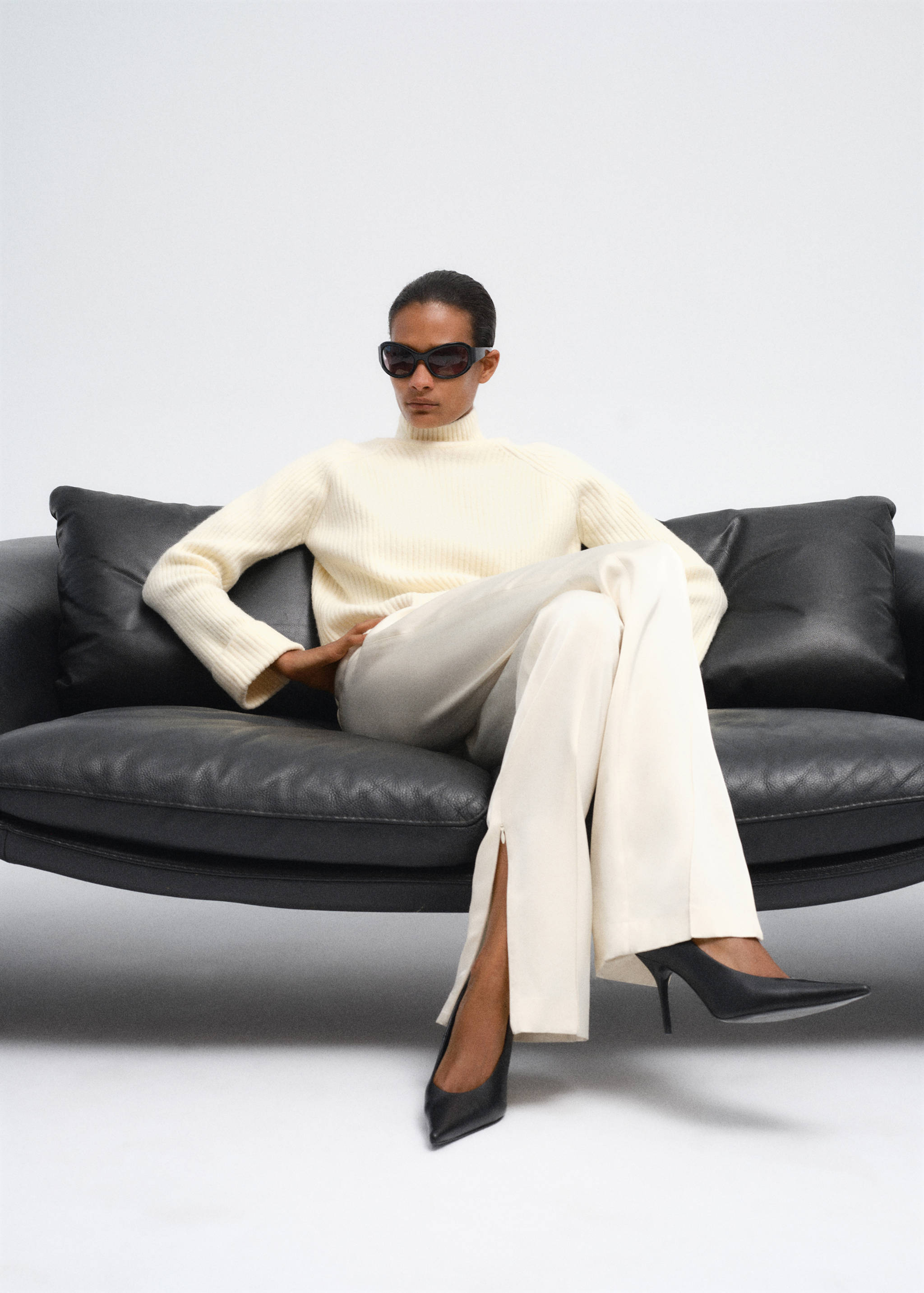 Cream ribbed turtleneck jumper worn with pale trousers and black heels.