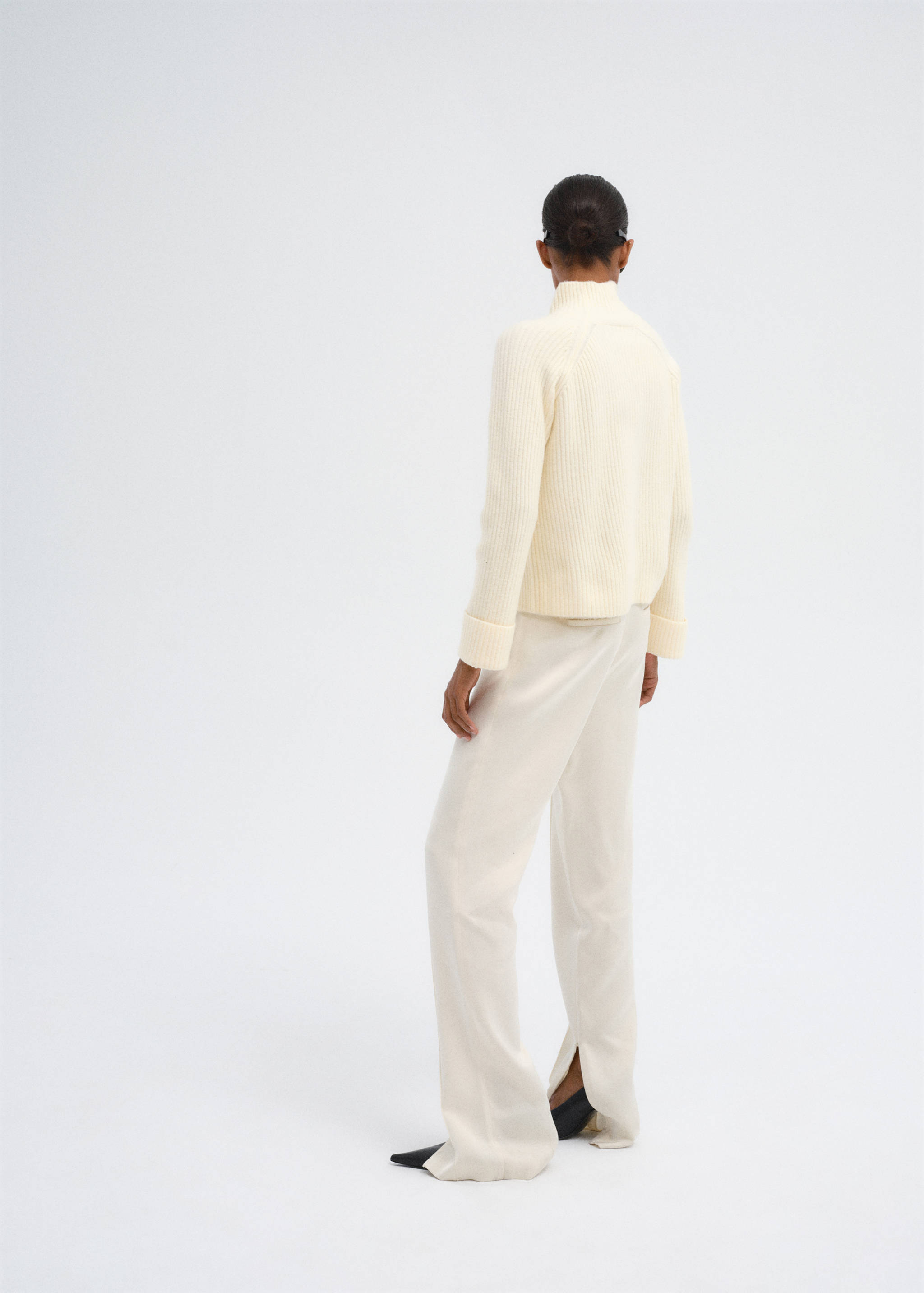 Back view of an off-white ribbed knit jumper with a high neck.