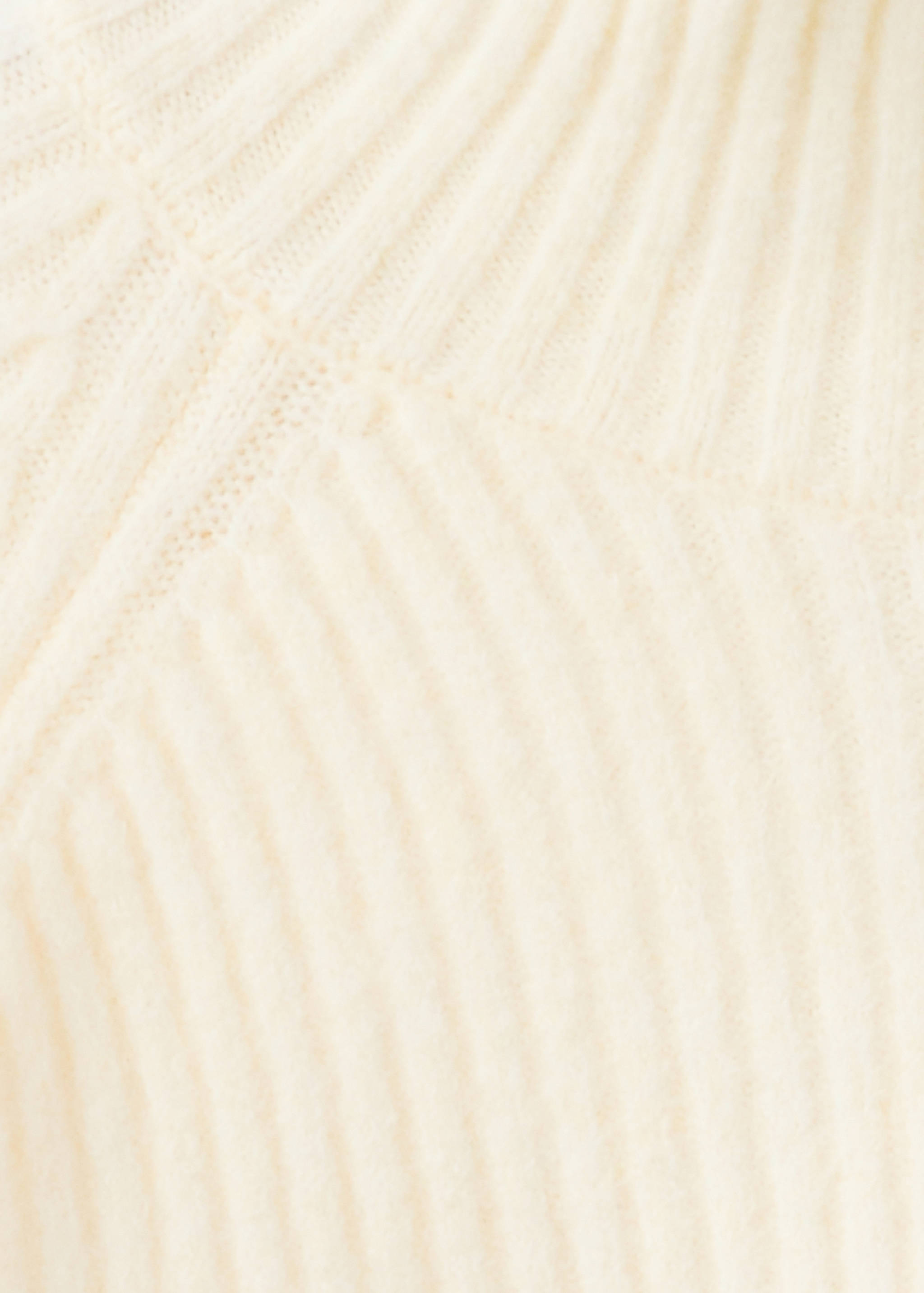 Close-up of the ribbed knit texture on a cream jumper.