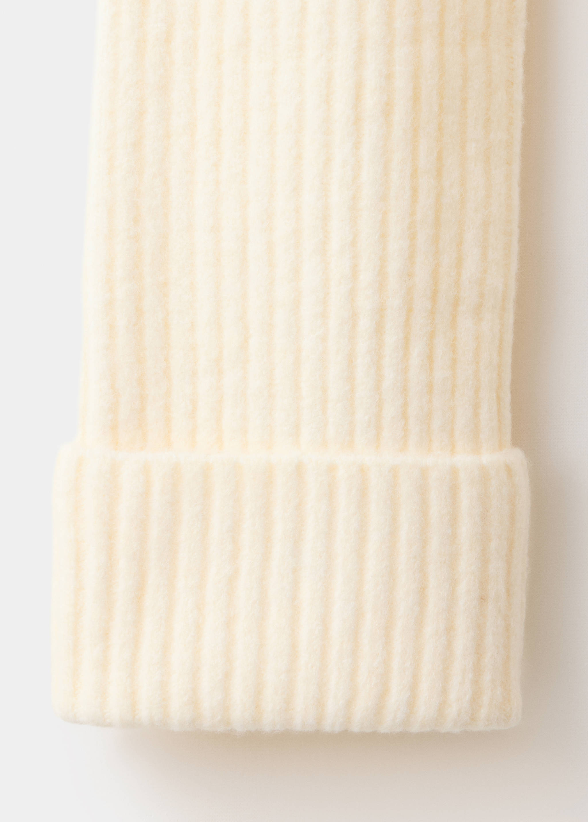 Cream knit sweater fabric detail showing the soft ribbed texture and cuff.