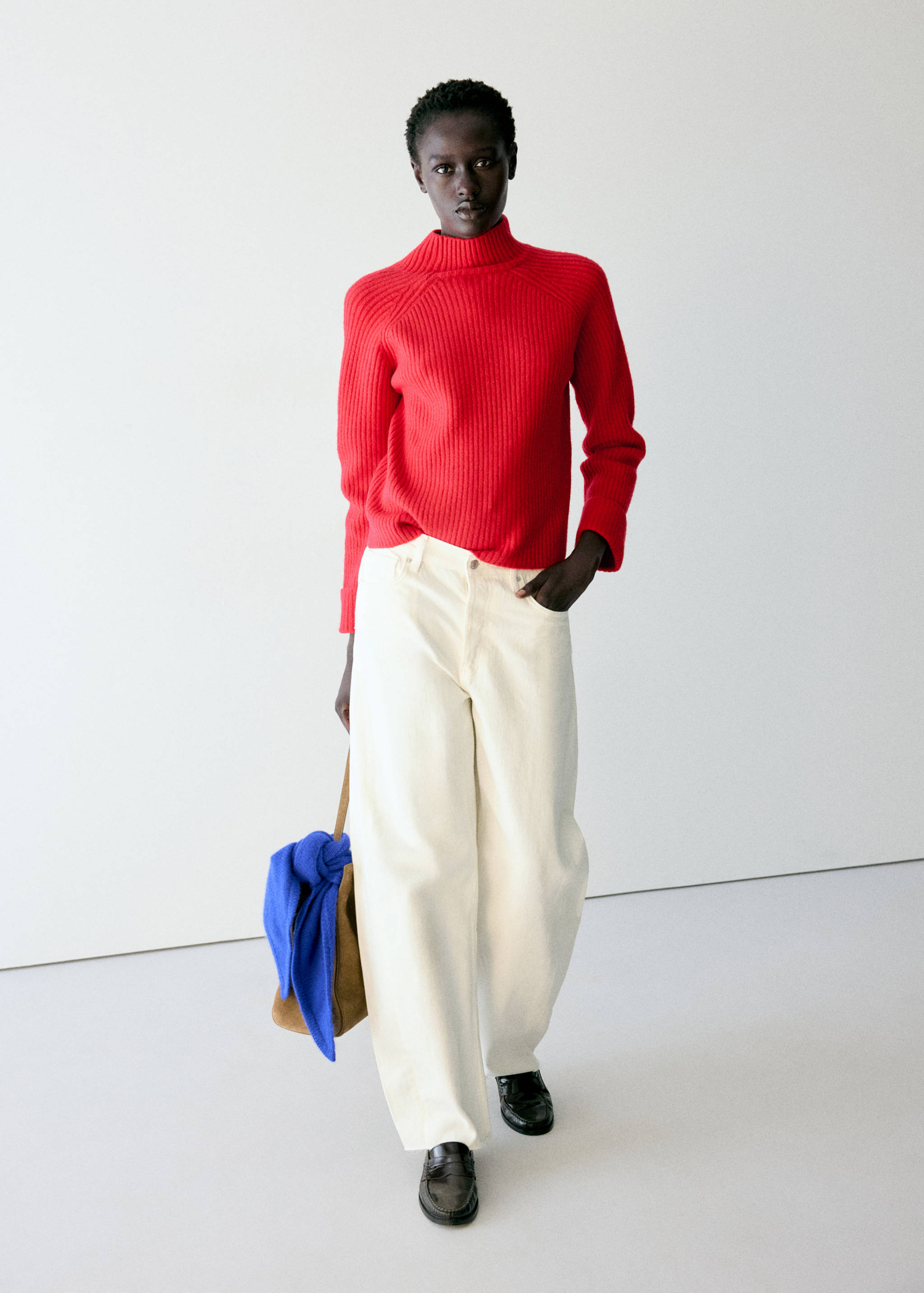Red ribbed knit jumper with a high neckline worn with cream trousers