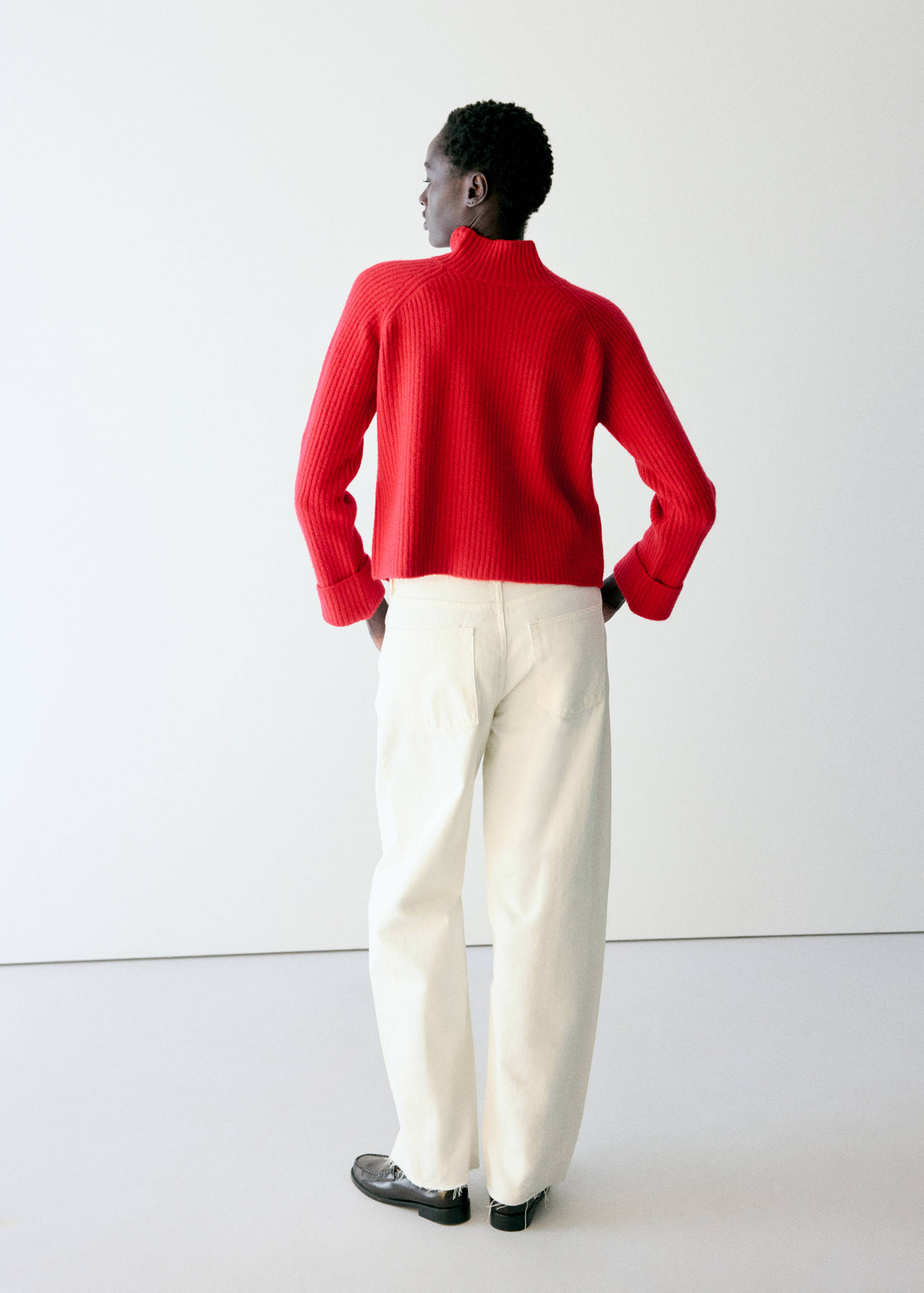 Red ribbed knit sweater with high neck and wide cuffs, back view.