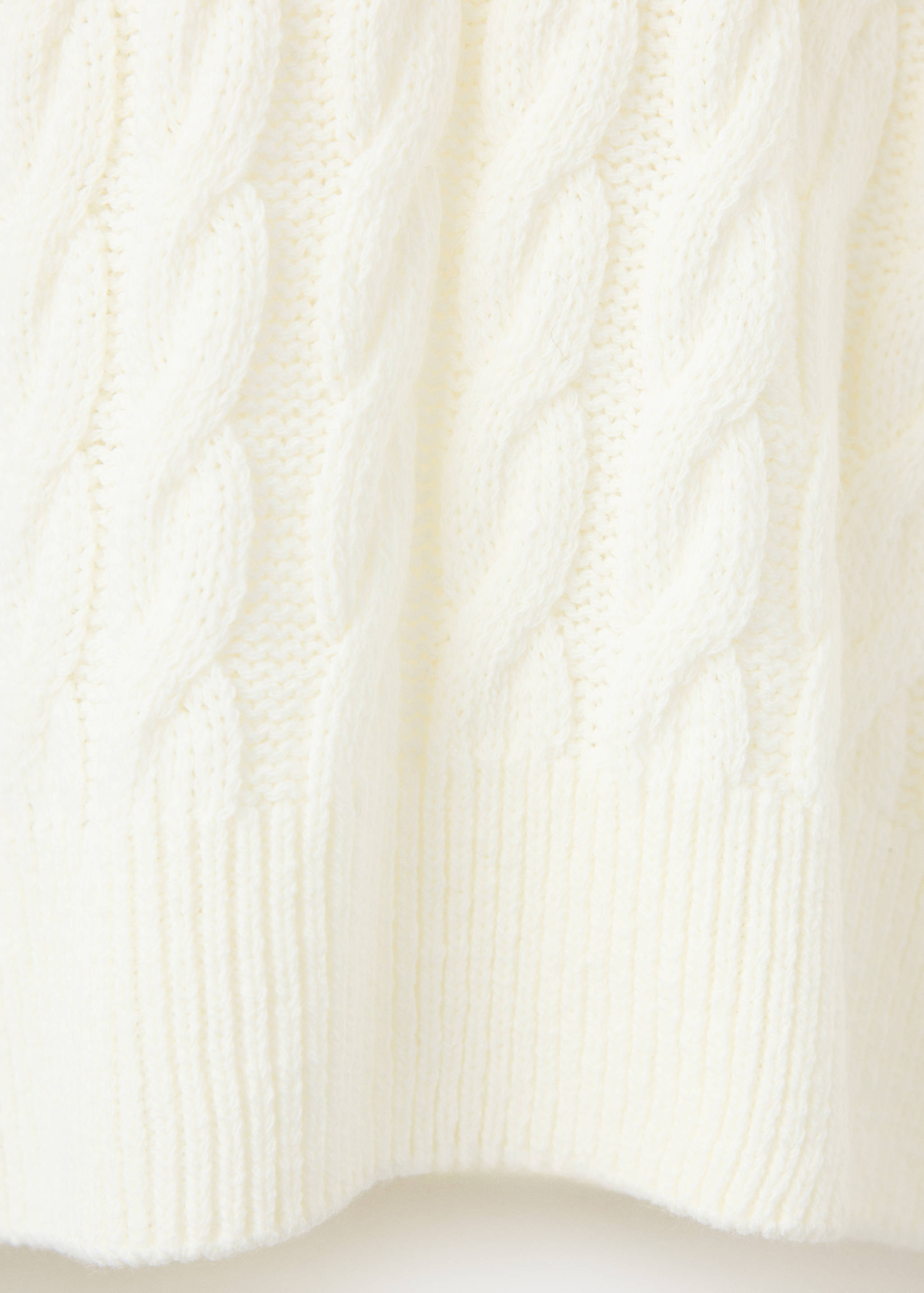 White cable-knit sweater texture detail with a ribbed hem.
